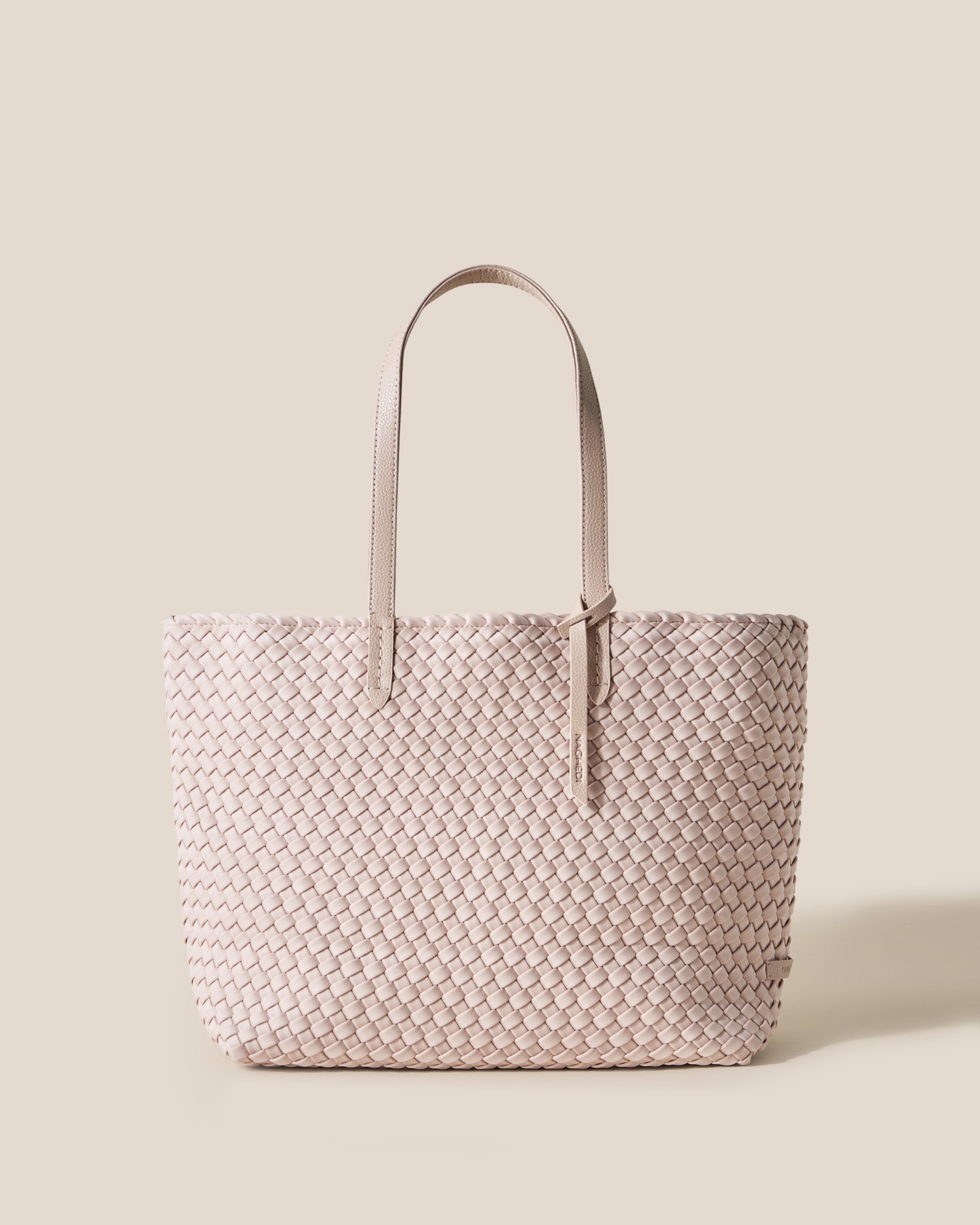 Jetsetter Tote in Shell Pink, a soft ballet pink tone, in handwoven neoprene, featuring a top zip closure, and vegan leather handles.