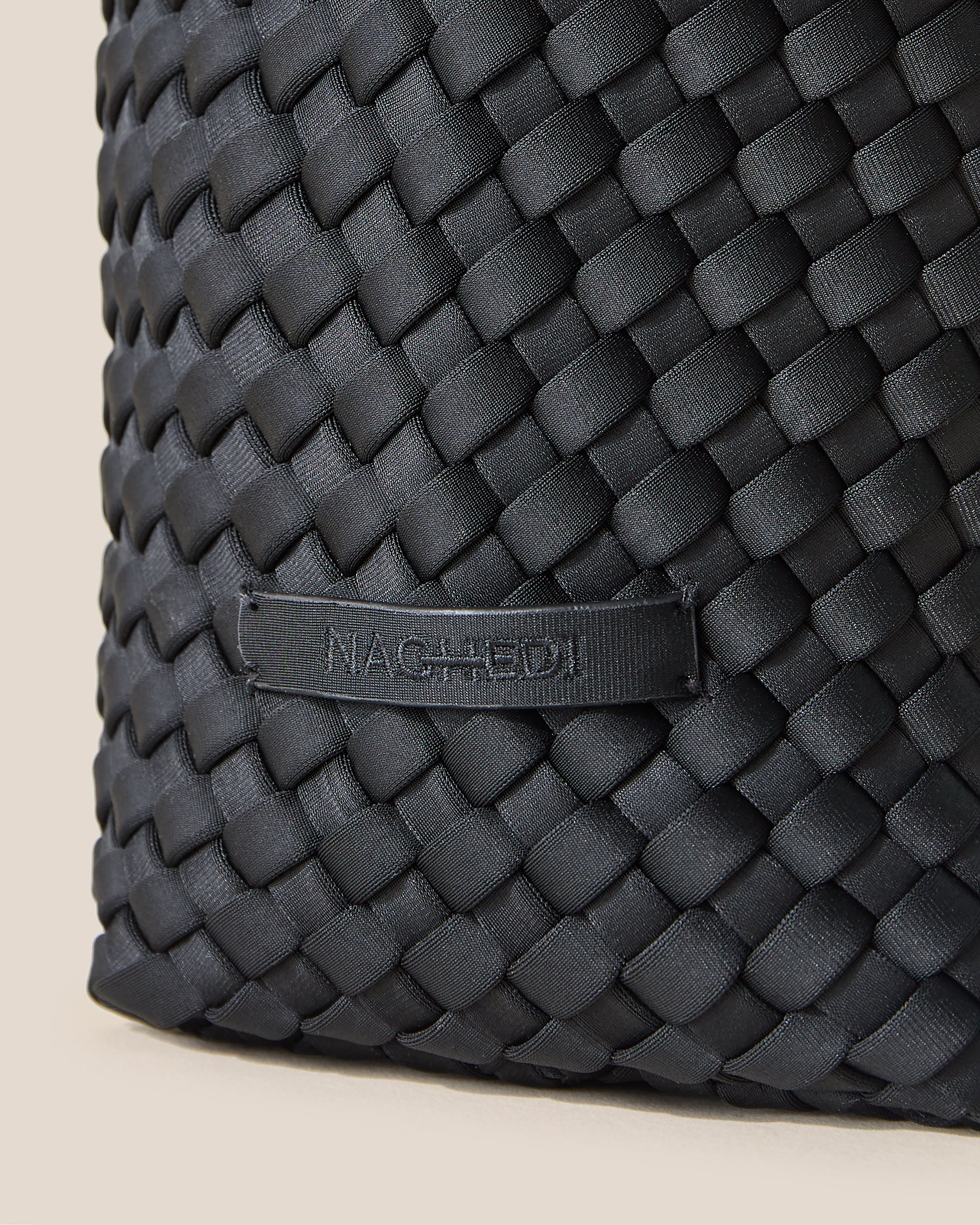 Close-up of stamped NAGHEDI logo on Laguna Crossbody in Onyx.