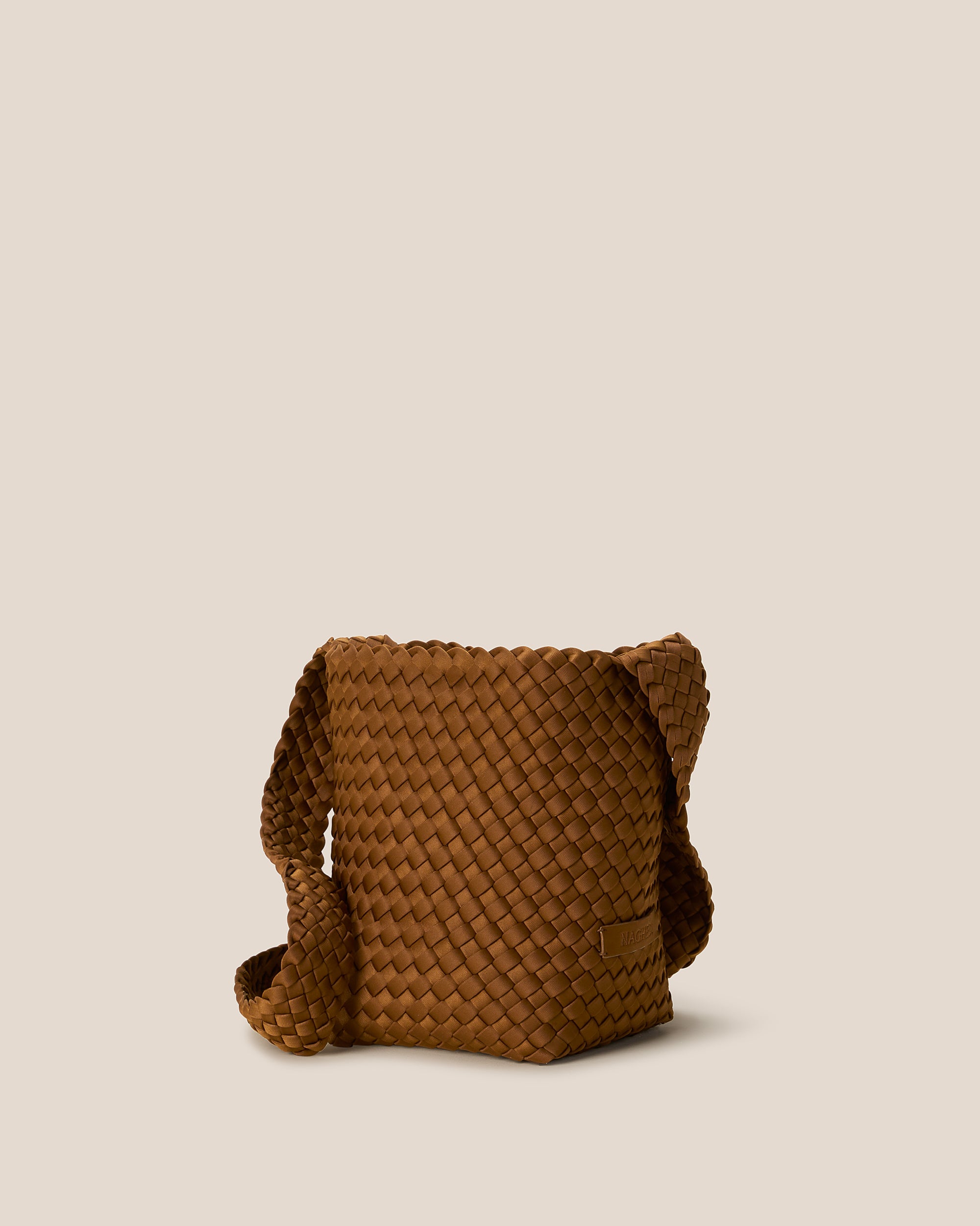 Laguna Crossbody in Teak shown from a side angle, highlighting its handwoven neoprene construction and open top with magnetic snap closure.