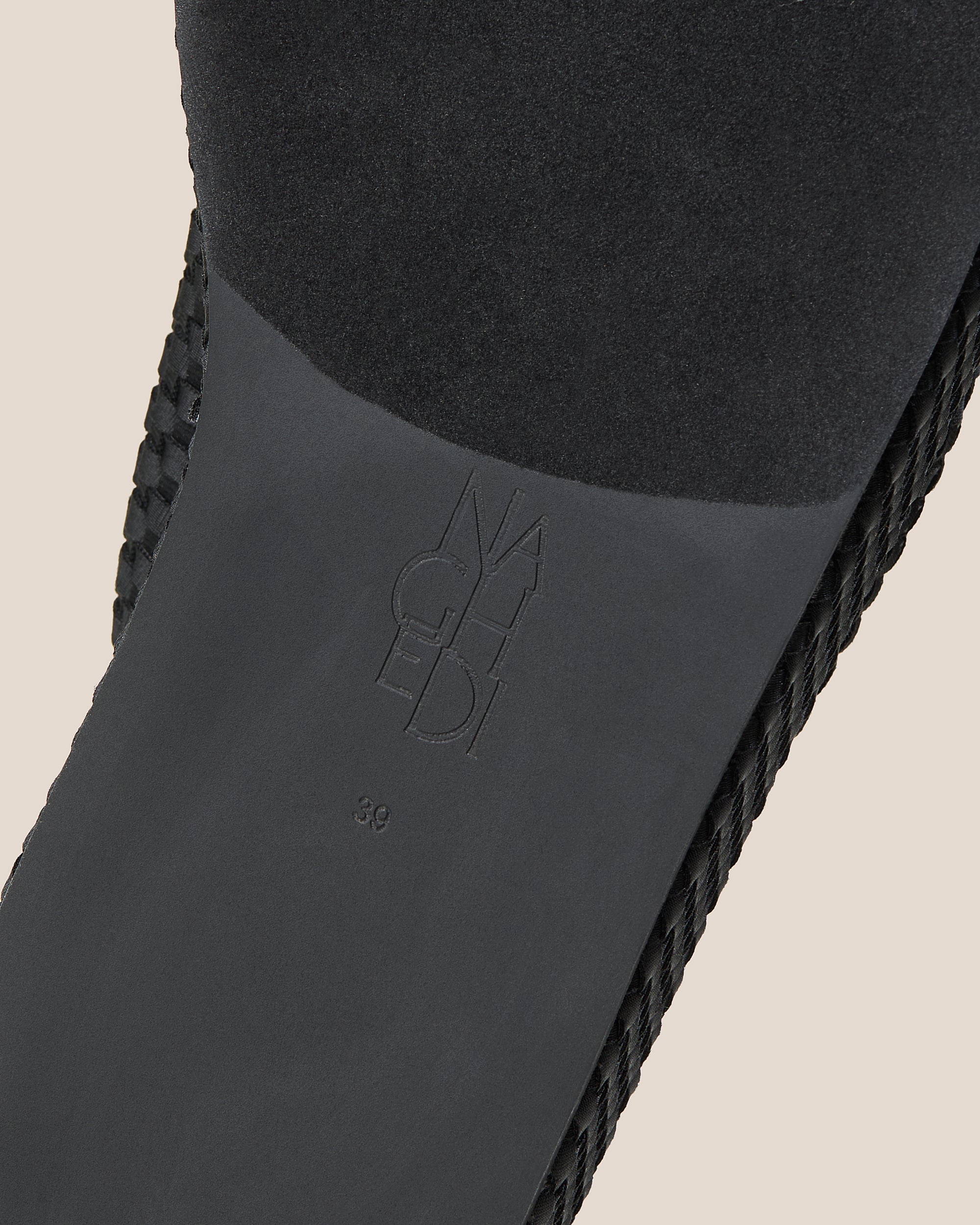 Shoe sole showing natural rubber sole, stamped NAGHEDI logo and size detail for The Laguna Platform in Onyx.