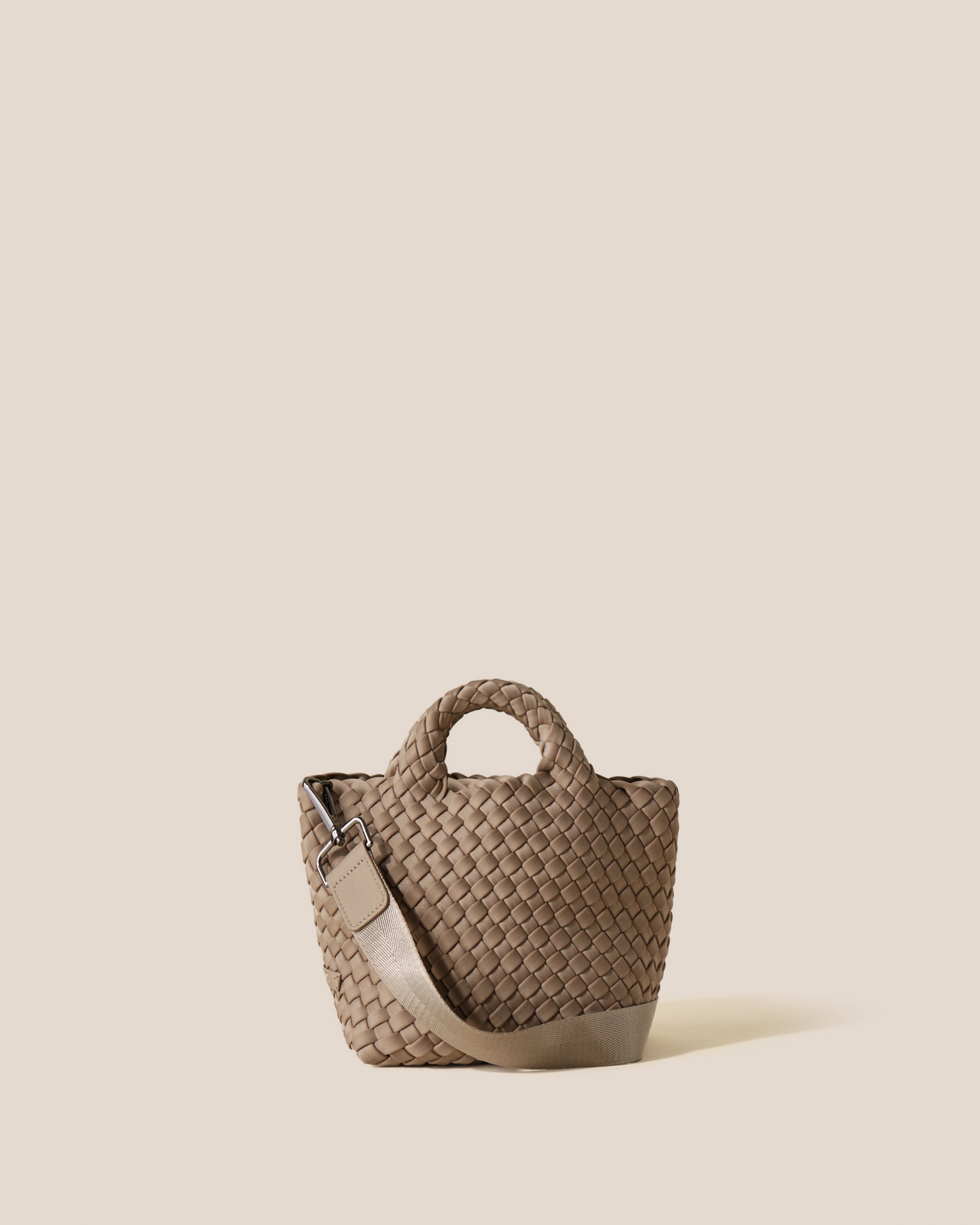 St. Barths Tote in Cashmere, a taupe tone, in handwoven neoprene, featuring an open top, woven top handles, and detachable, adjustable nylon crossbody strap.
