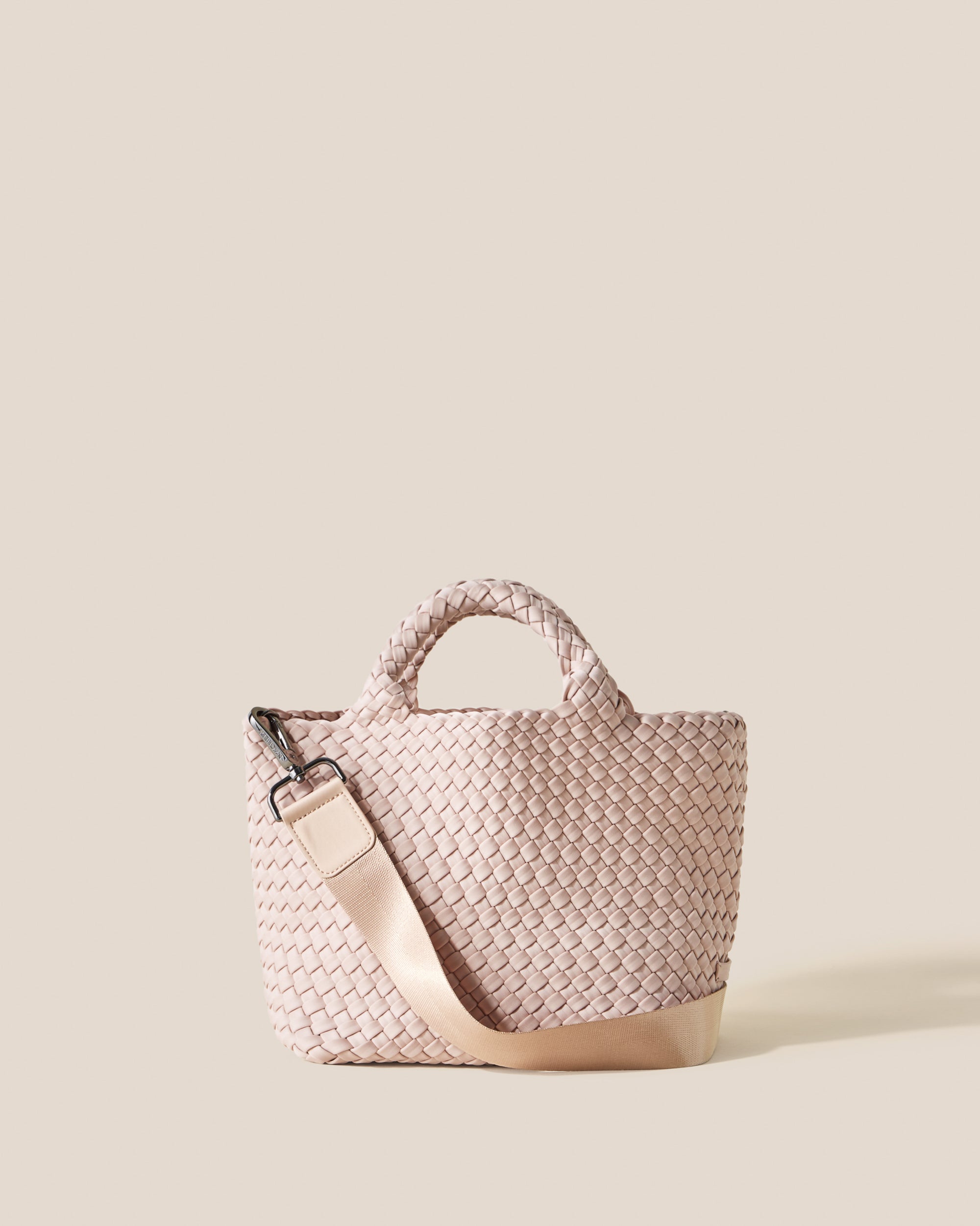 St. Barths Tote in Shell Pink, a soft ballet pink tone, in handwoven neoprene, featuring an open top, woven top handles, and detachable, adjustable nylon crossbody strap.