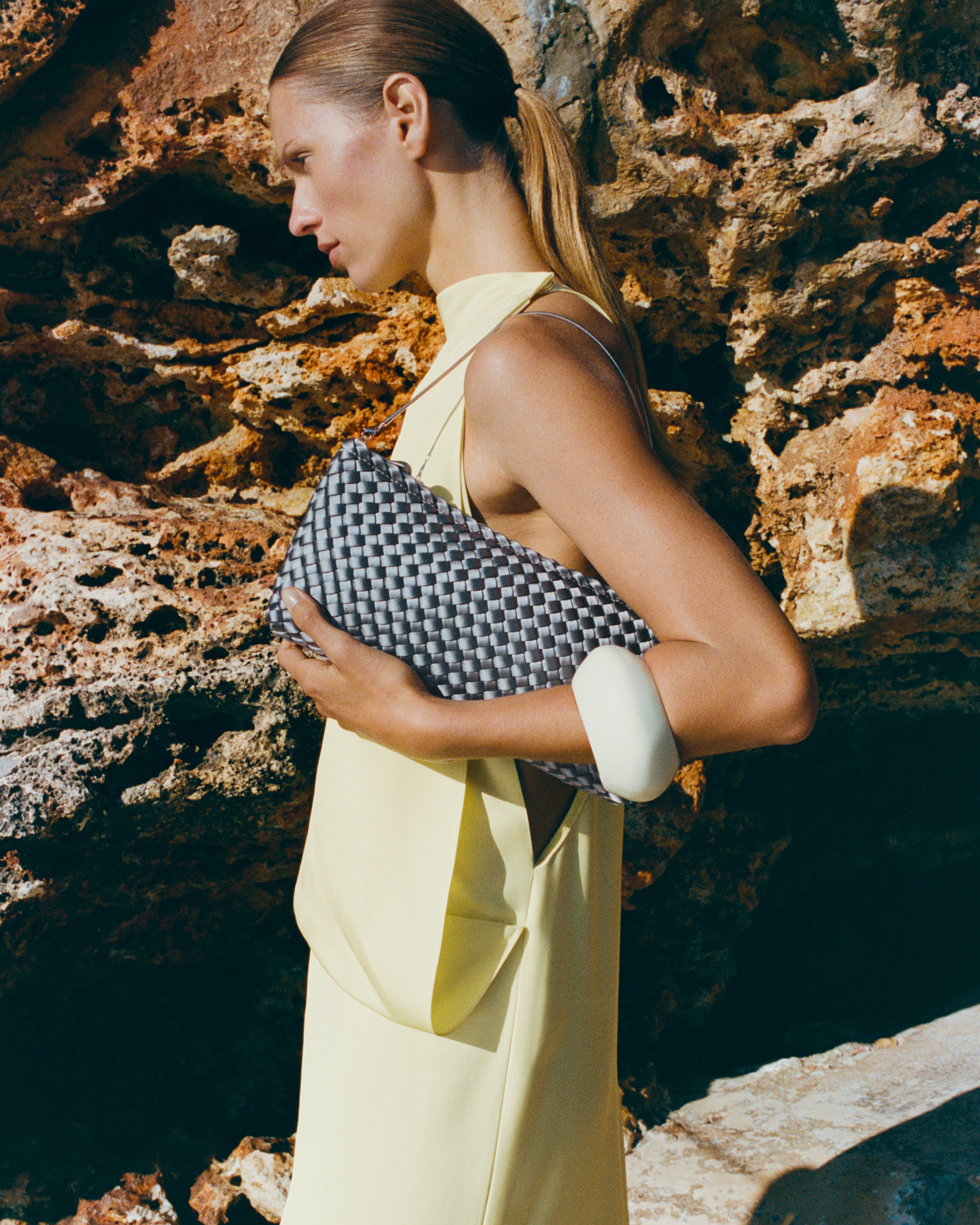 On model close up of the Gala Clutch in Graphite. Highlighting the handwoven satin and the removable silver chain.