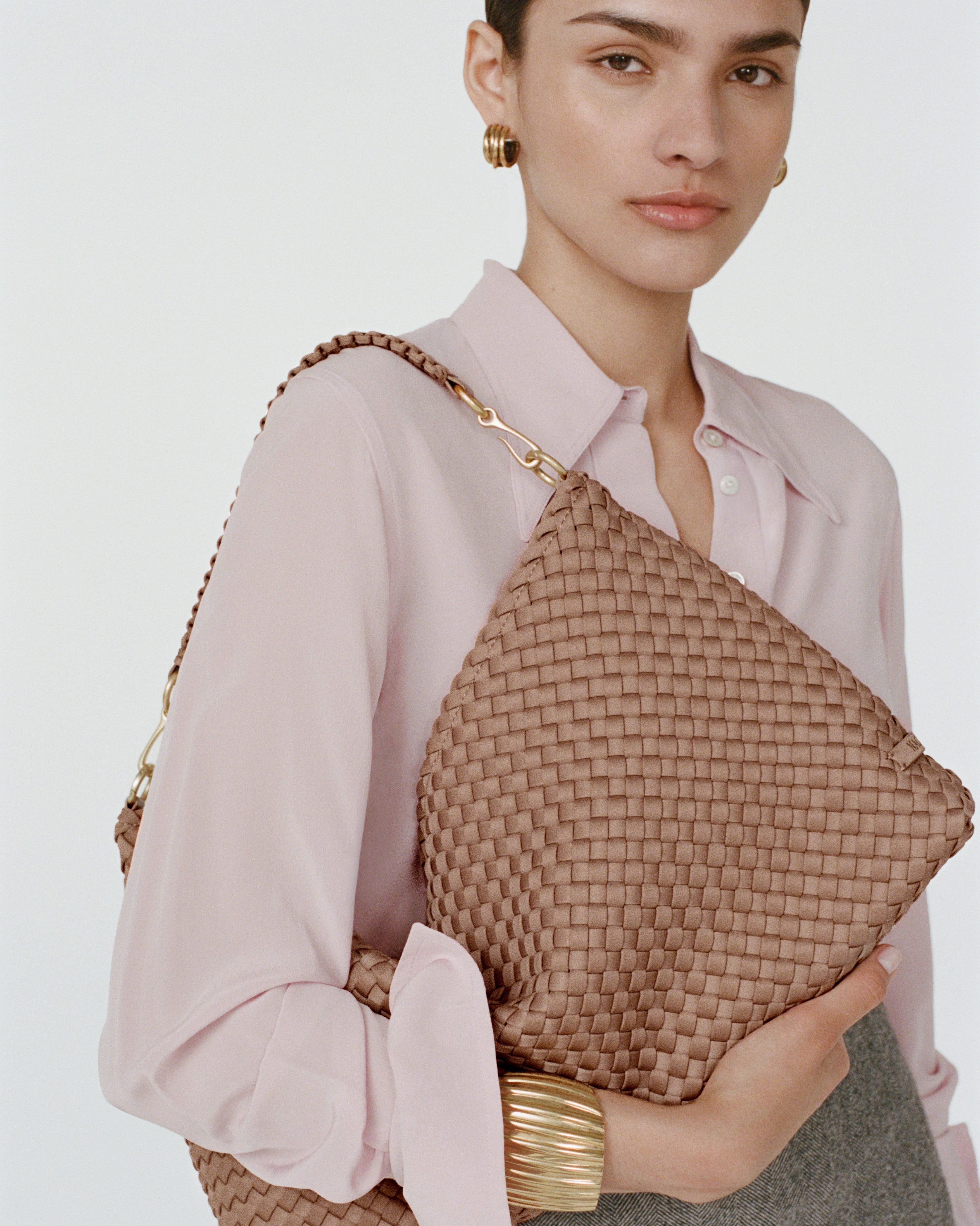 Model in light pink blouse holding the Porto Medium Half Moon Shoulder Bag in Seychelles over her right shoulder