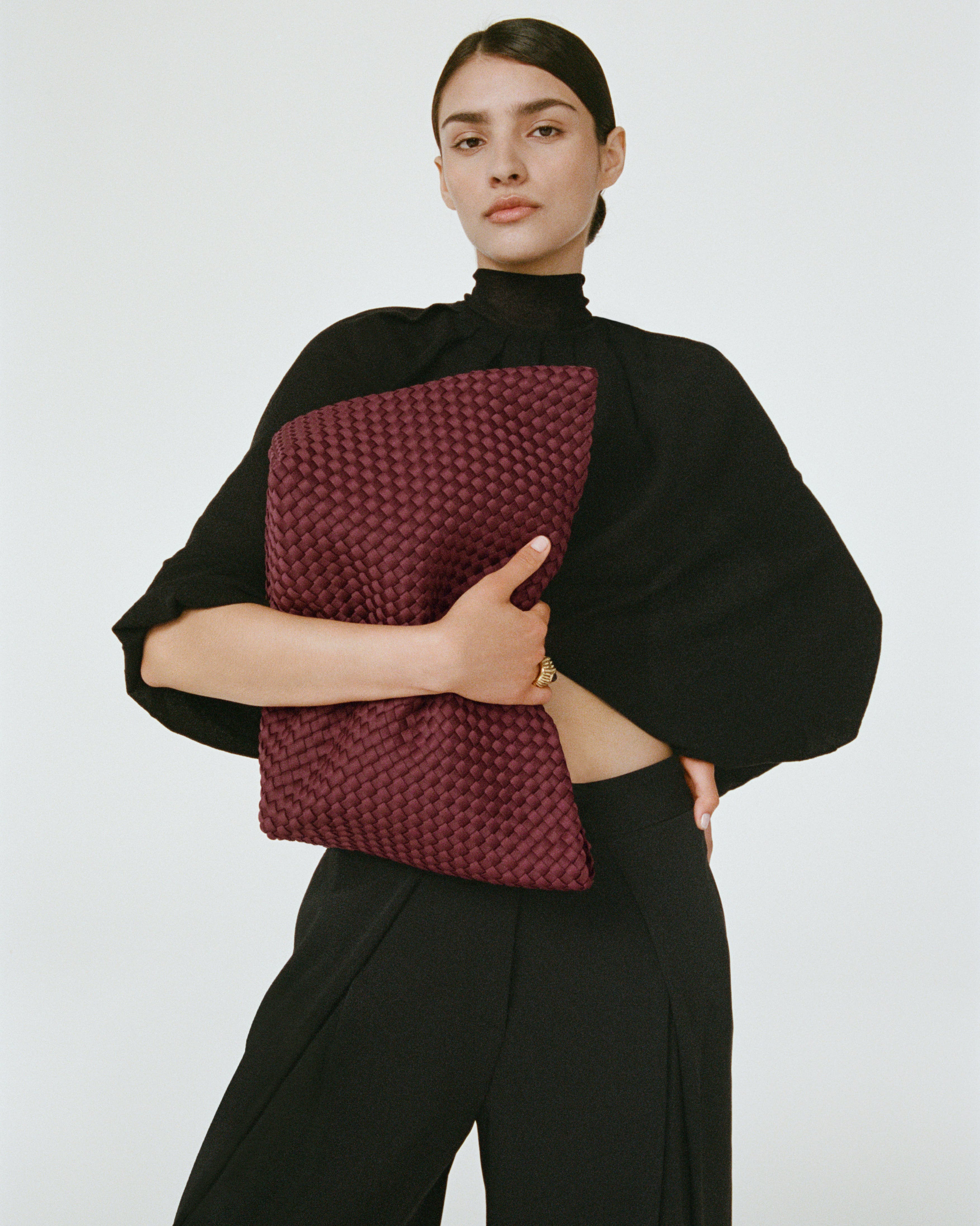 Editorial shot of model holding St. Barths Tote in Bordeaux with one arm close to her body.
