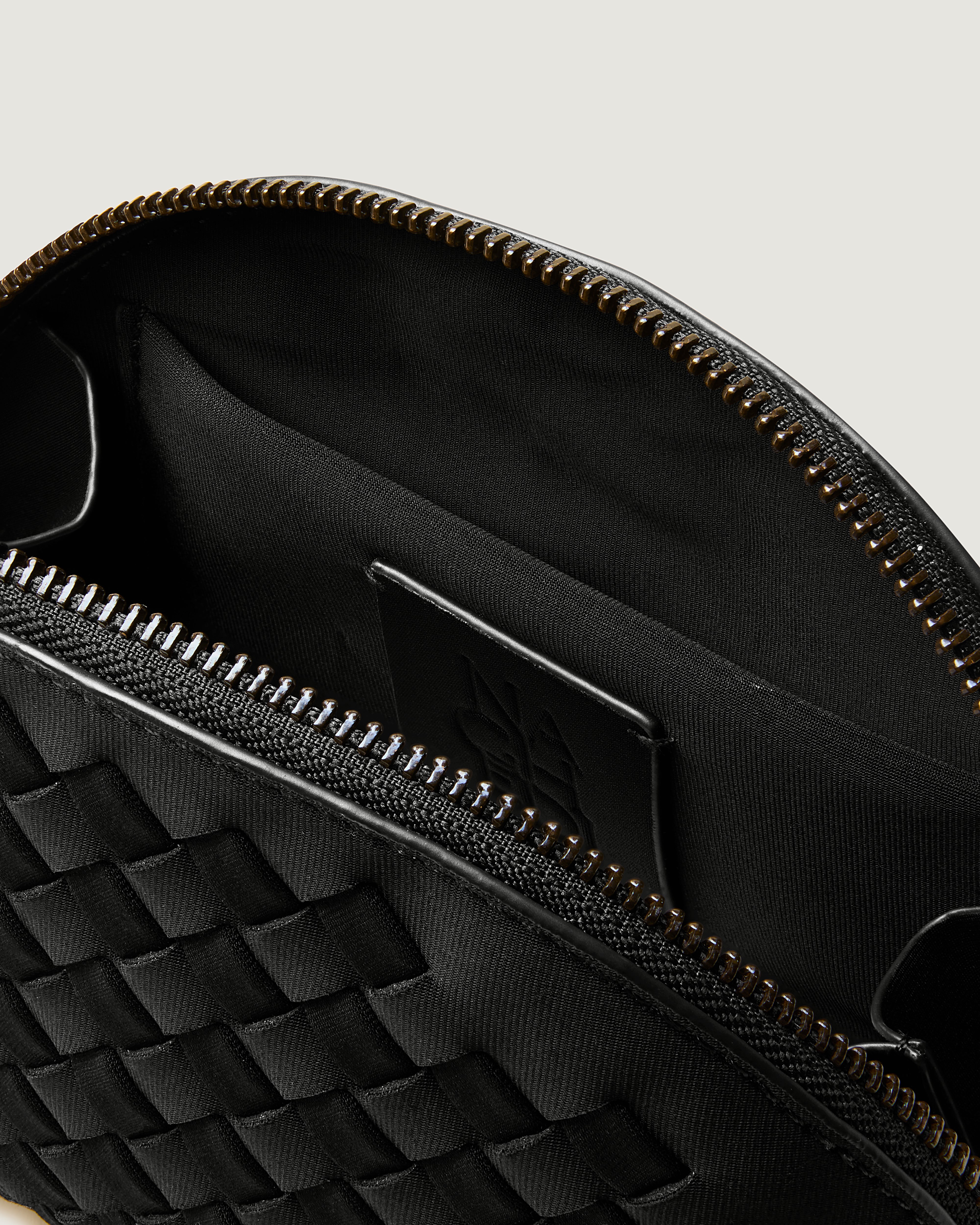 Close-up of stamped NAGHEDI logo, interior pocket and wipe-clean lining in Atlas Cosmetic Case in Onyx.