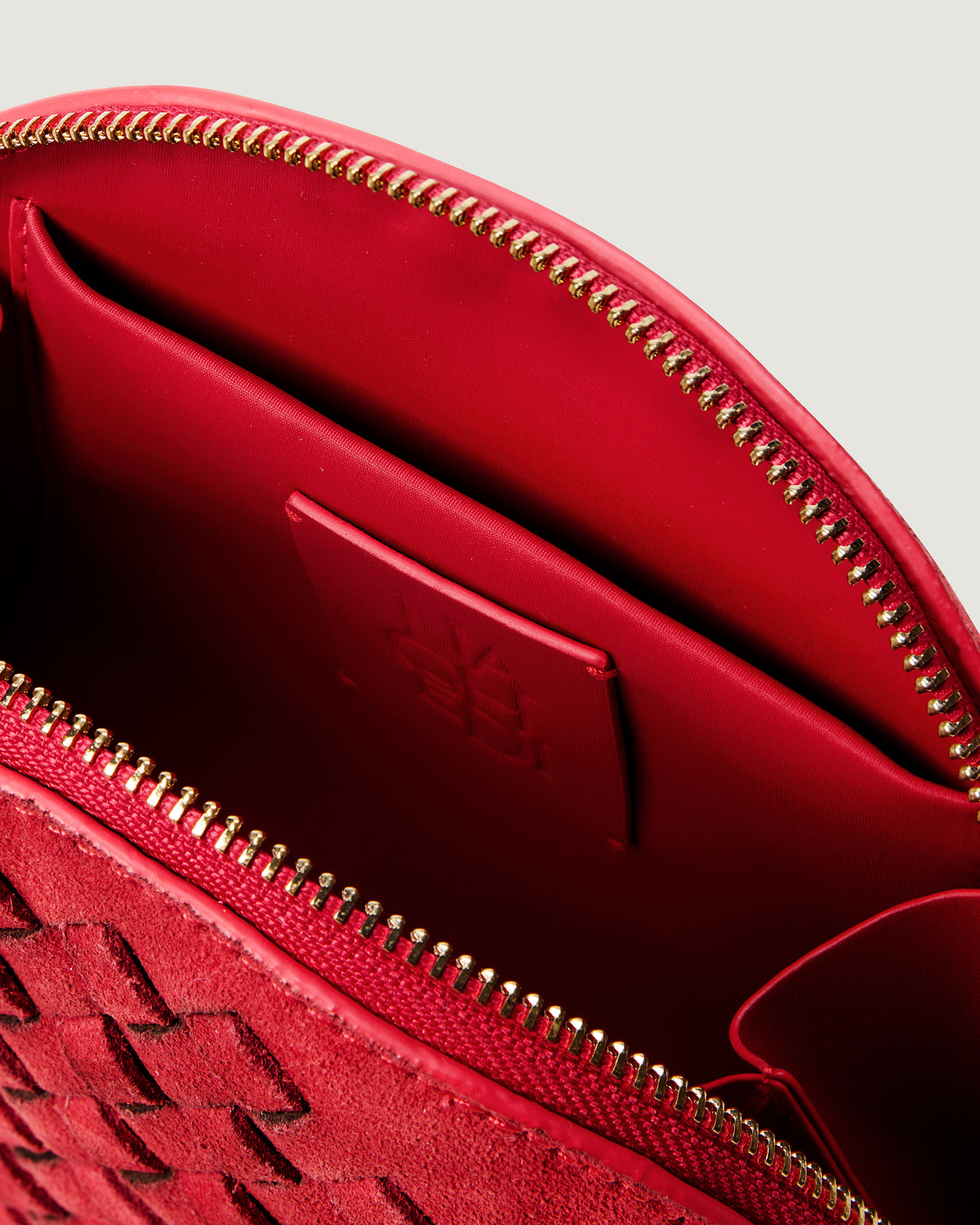 Close-up of stamped NAGHEDI logo, interior pocket and wipe-clean lining in Atlas Cosmetic Case in Cerise.