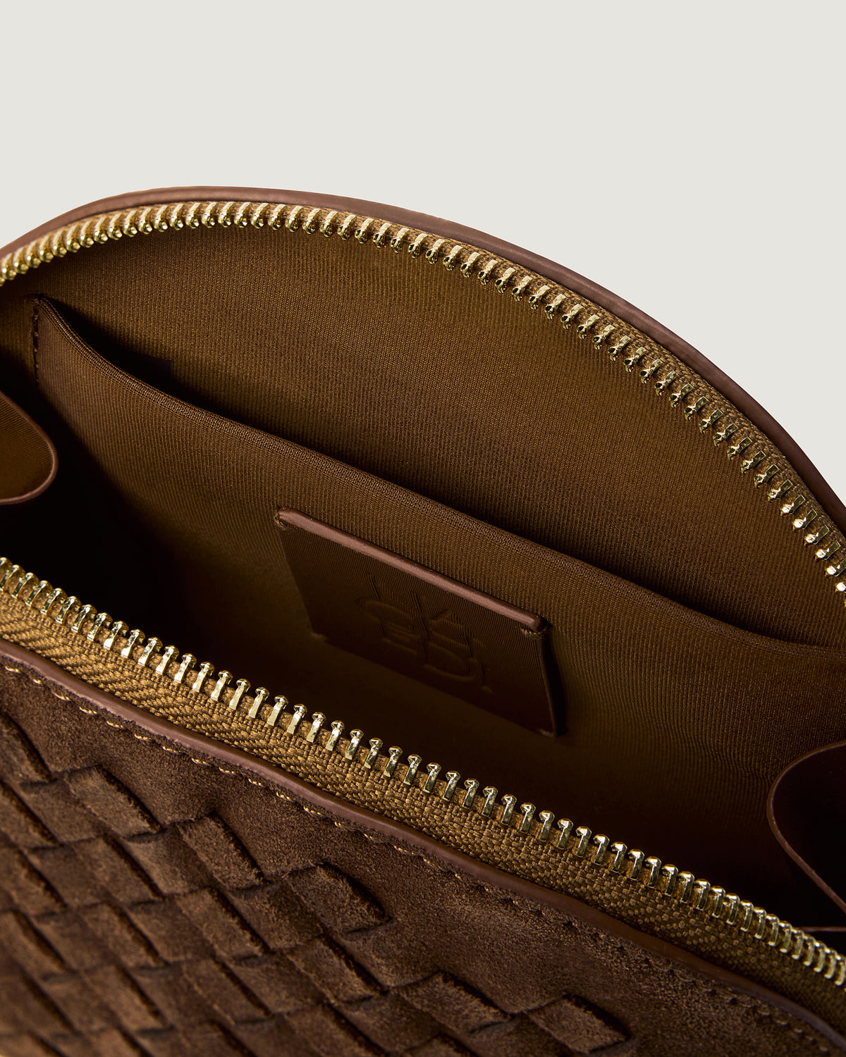 Close-up of stamped NAGHEDI logo, interior pocket and wipe-clean lining in Atlas Cosmetic Case in Teak.