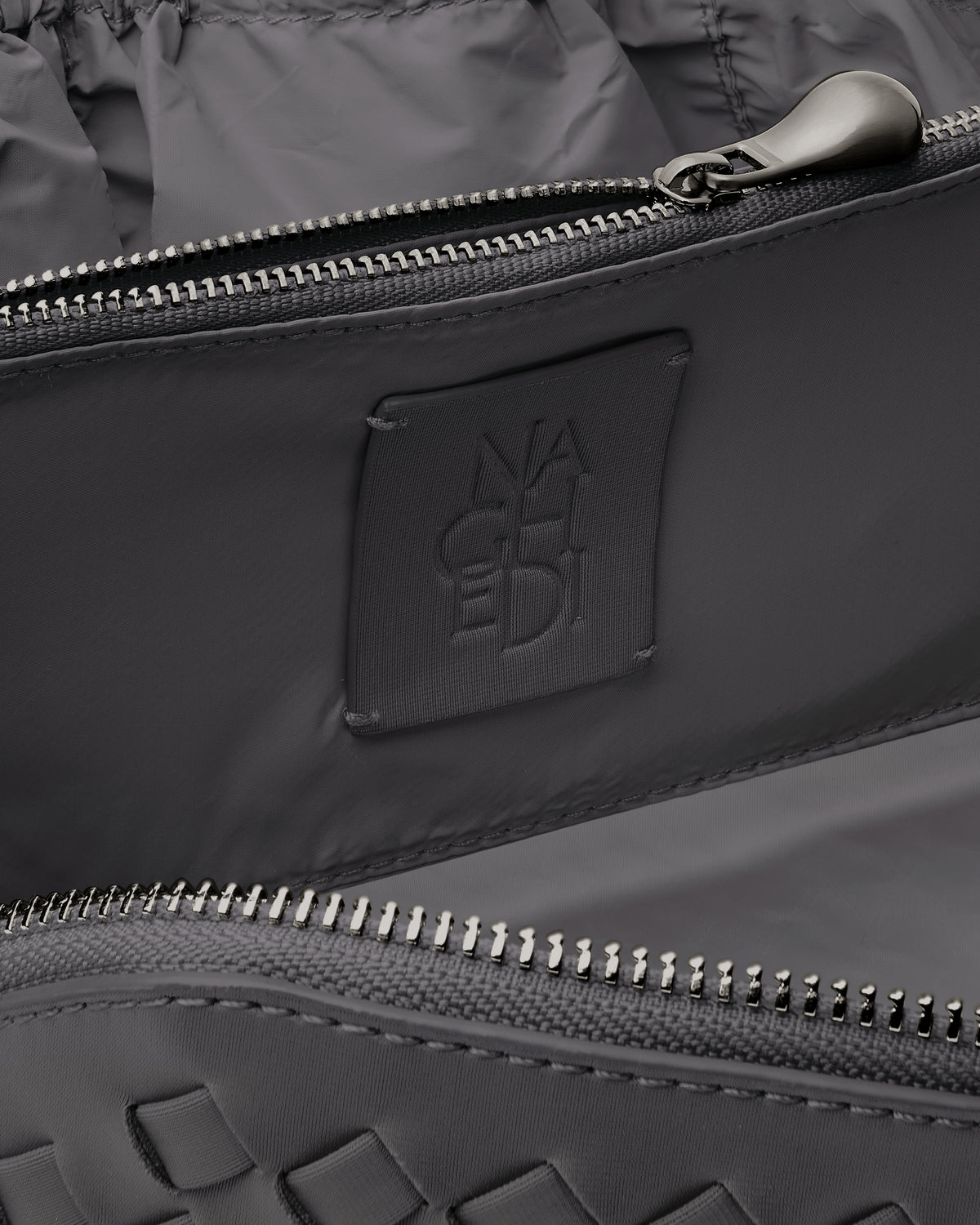 Close-up of stamped NAGHEDI logo, interior pocket and wipe-clean nylon lining in Caravan Cosmetic Case in Ash.