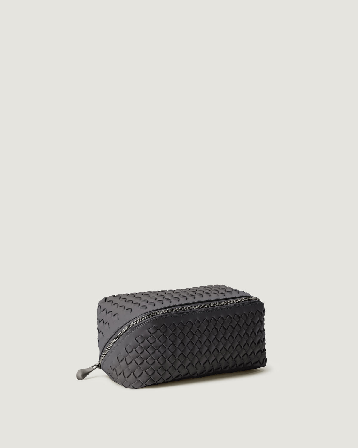 Caravan Cosmetic Case in Ash shown from a side angle, highlighting its handwoven neoprene construction and wrap-around zip closure.