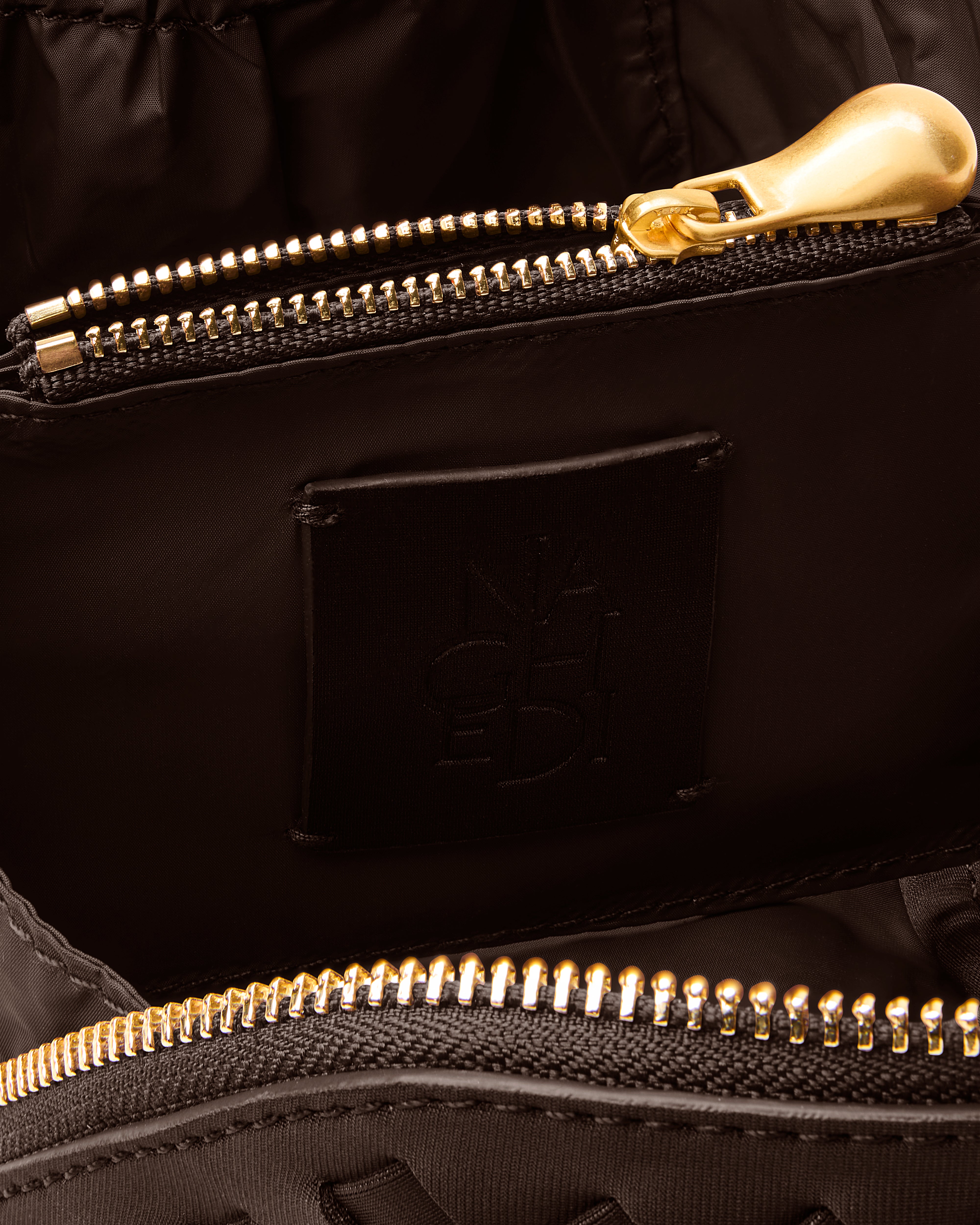 Close-up of stamped NAGHEDI logo, interior pocket and wipe-clean nylon lining in Caravan Cosmetic Case in Chocolate.
