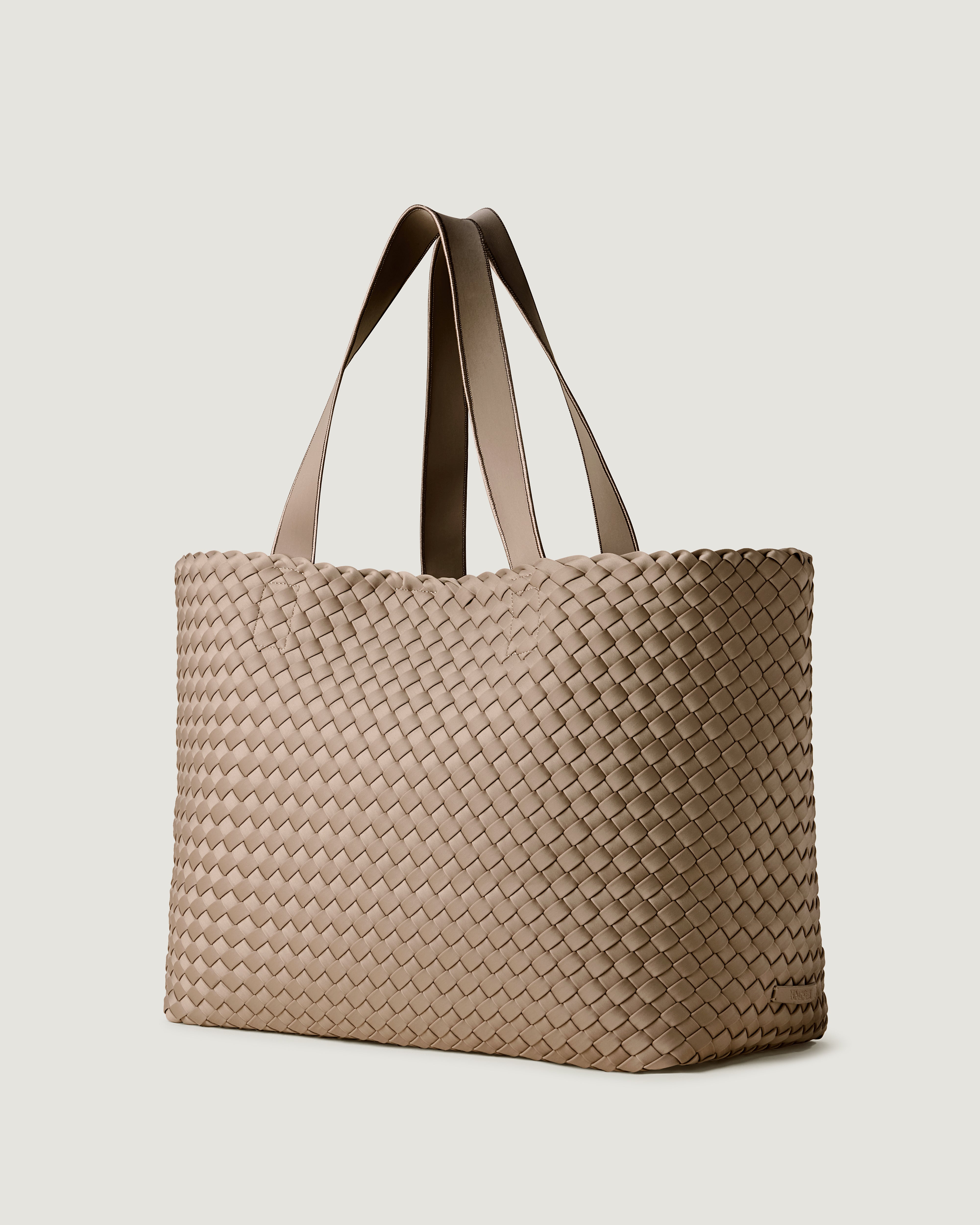 Como Tote in Cashmere shown from a side angle, highlighting its handwoven neoprene construction and open top with magnetic snap closure.