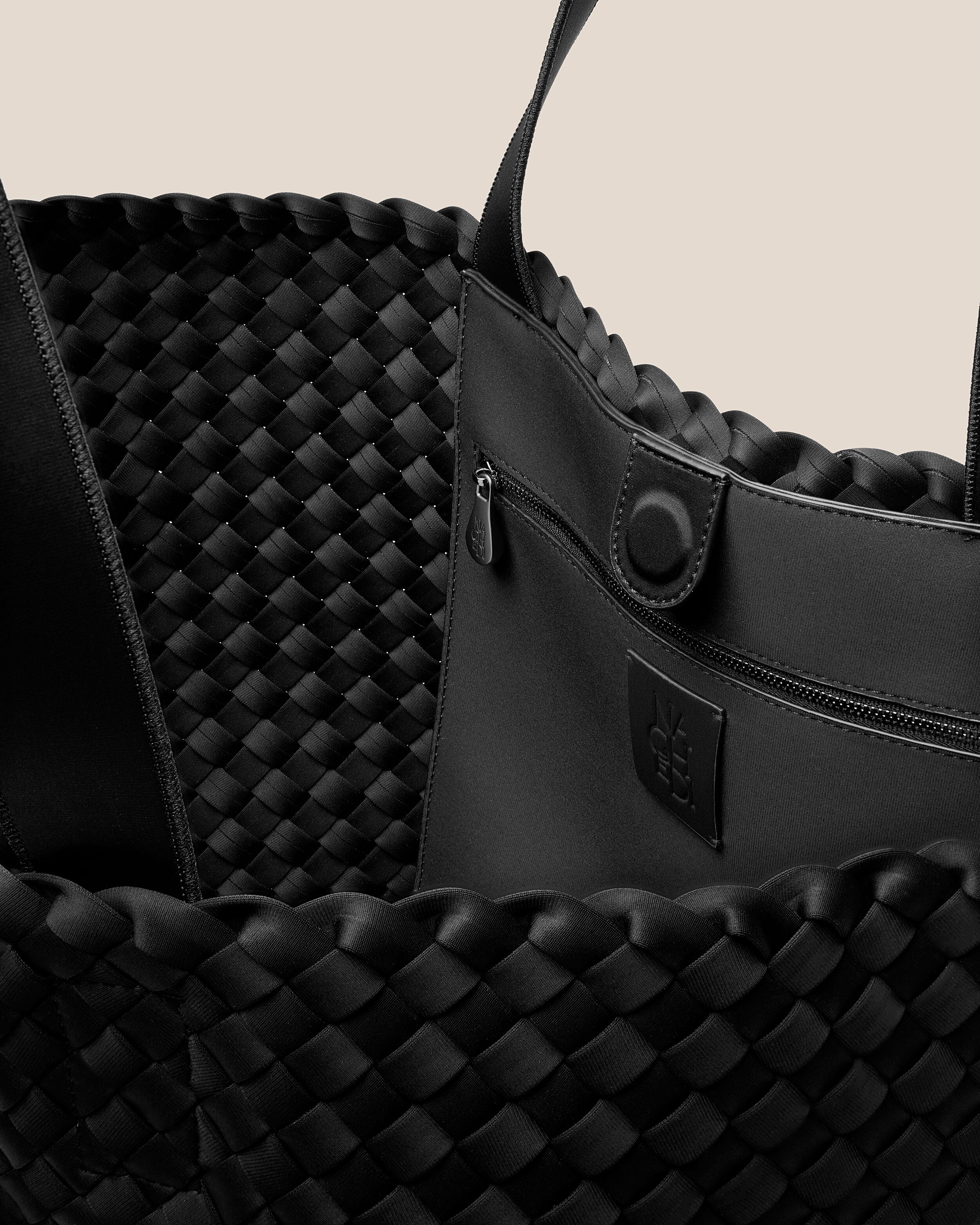 Interior close-up of Como Tote in Onyx showing its open top with magnetic snap closure, interior zip pocket, and unlined interior.