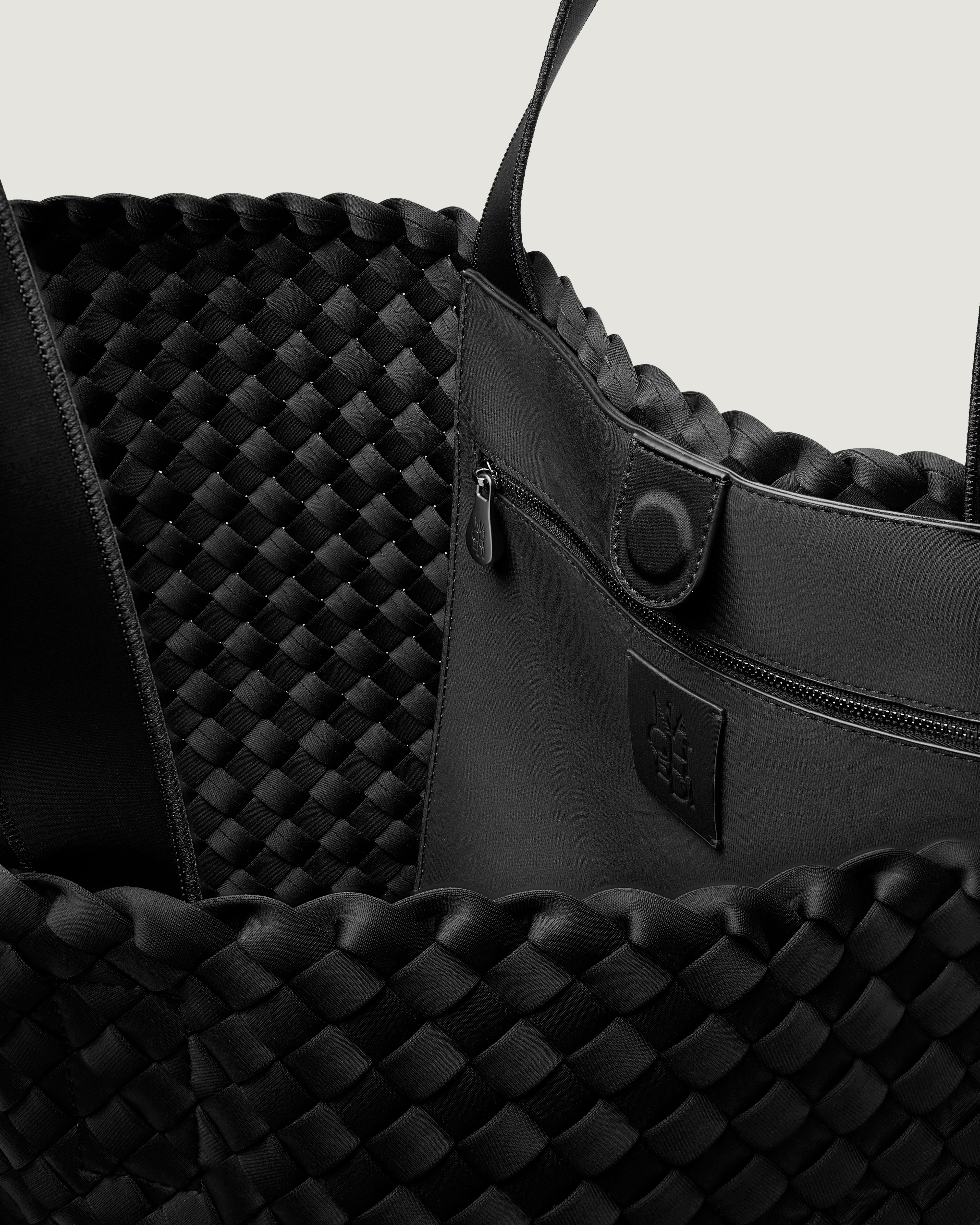 Interior close-up of Como Tote in Onyx showing its open top with magnetic snap closure, interior zip pocket, and unlined interior.