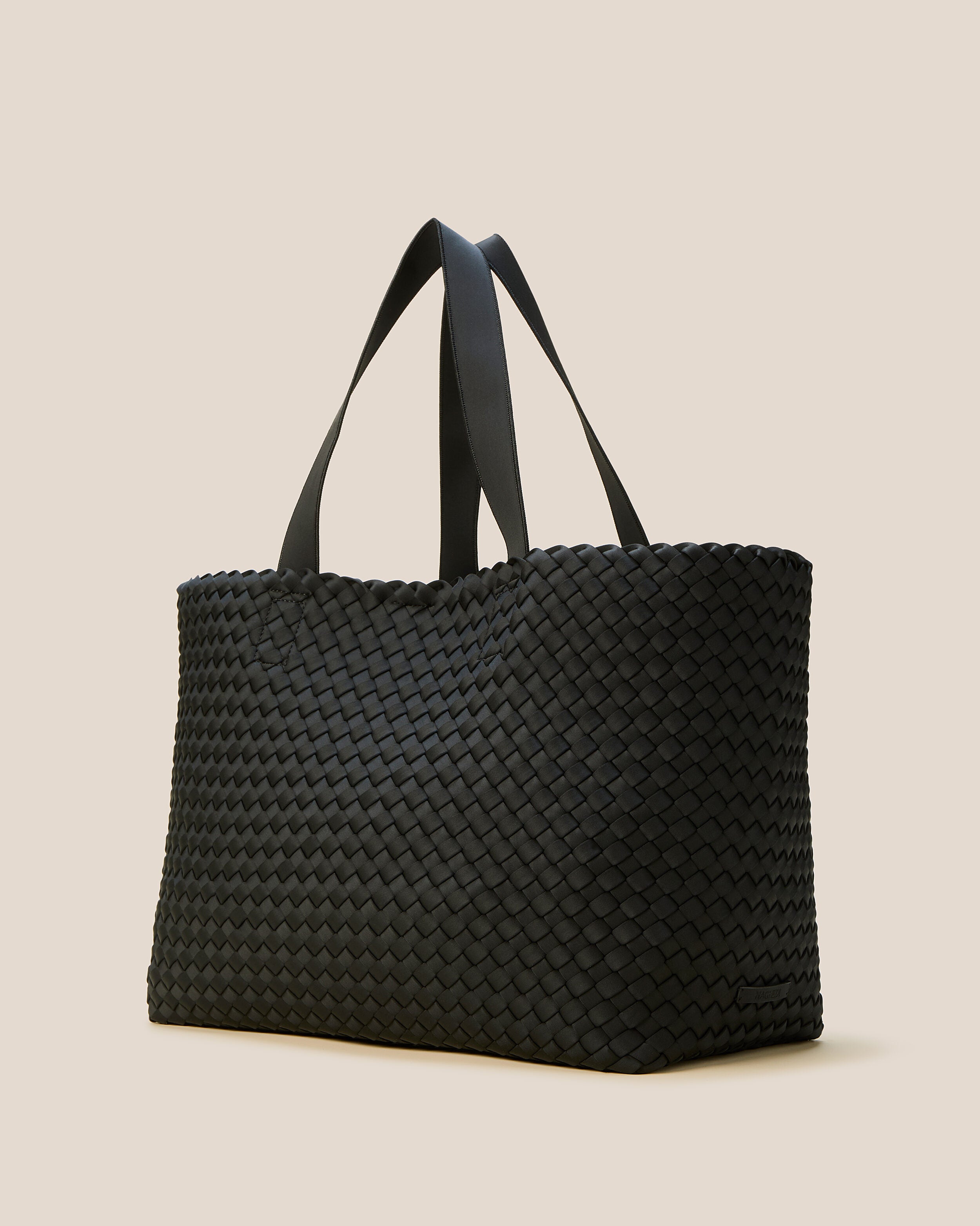 Como Tote in Onyx shown from a side angle, highlighting its handwoven neoprene construction and open top with magnetic snap closure.