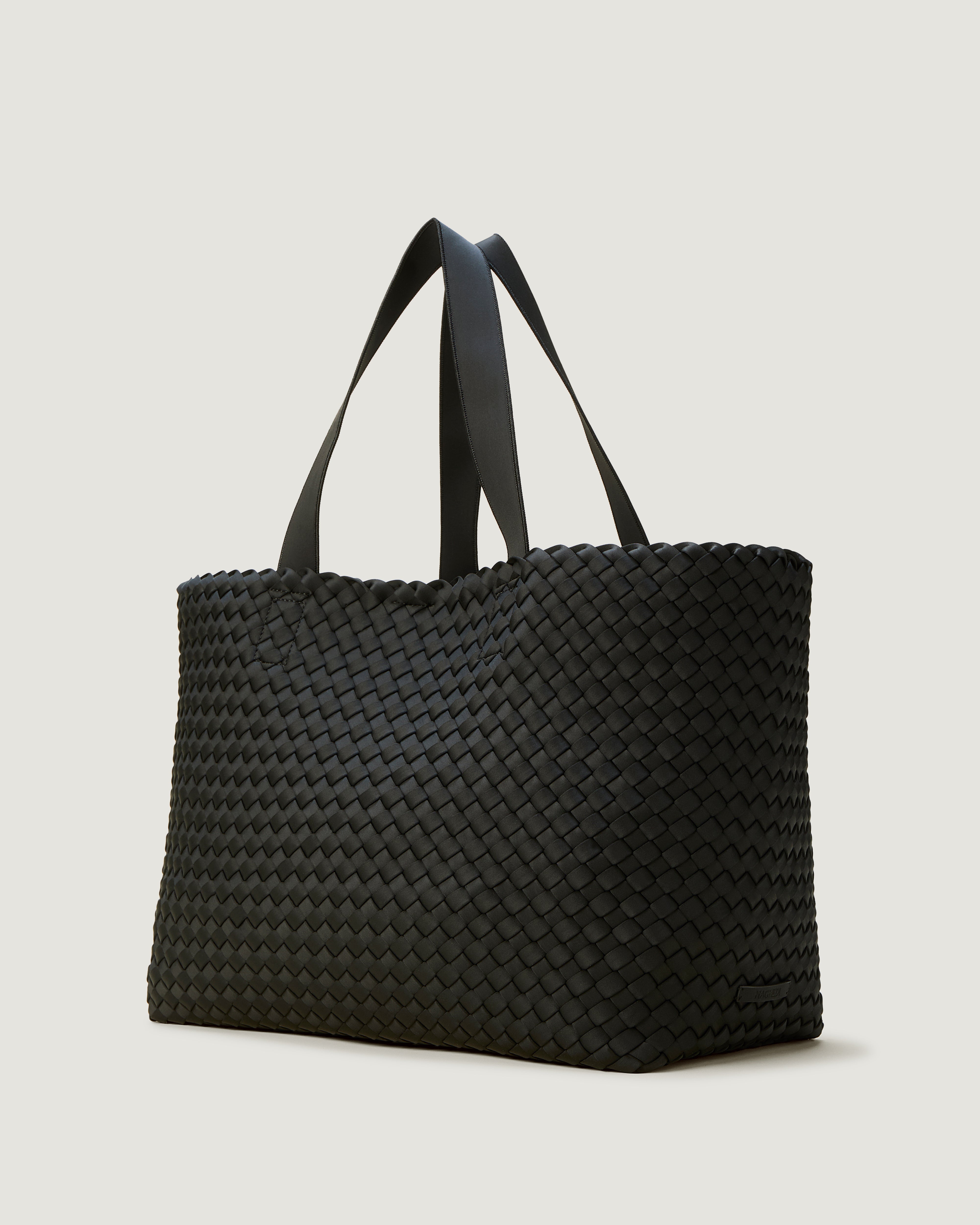Como Tote in Onyx shown from a side angle, highlighting its handwoven neoprene construction and open top with magnetic snap closure.