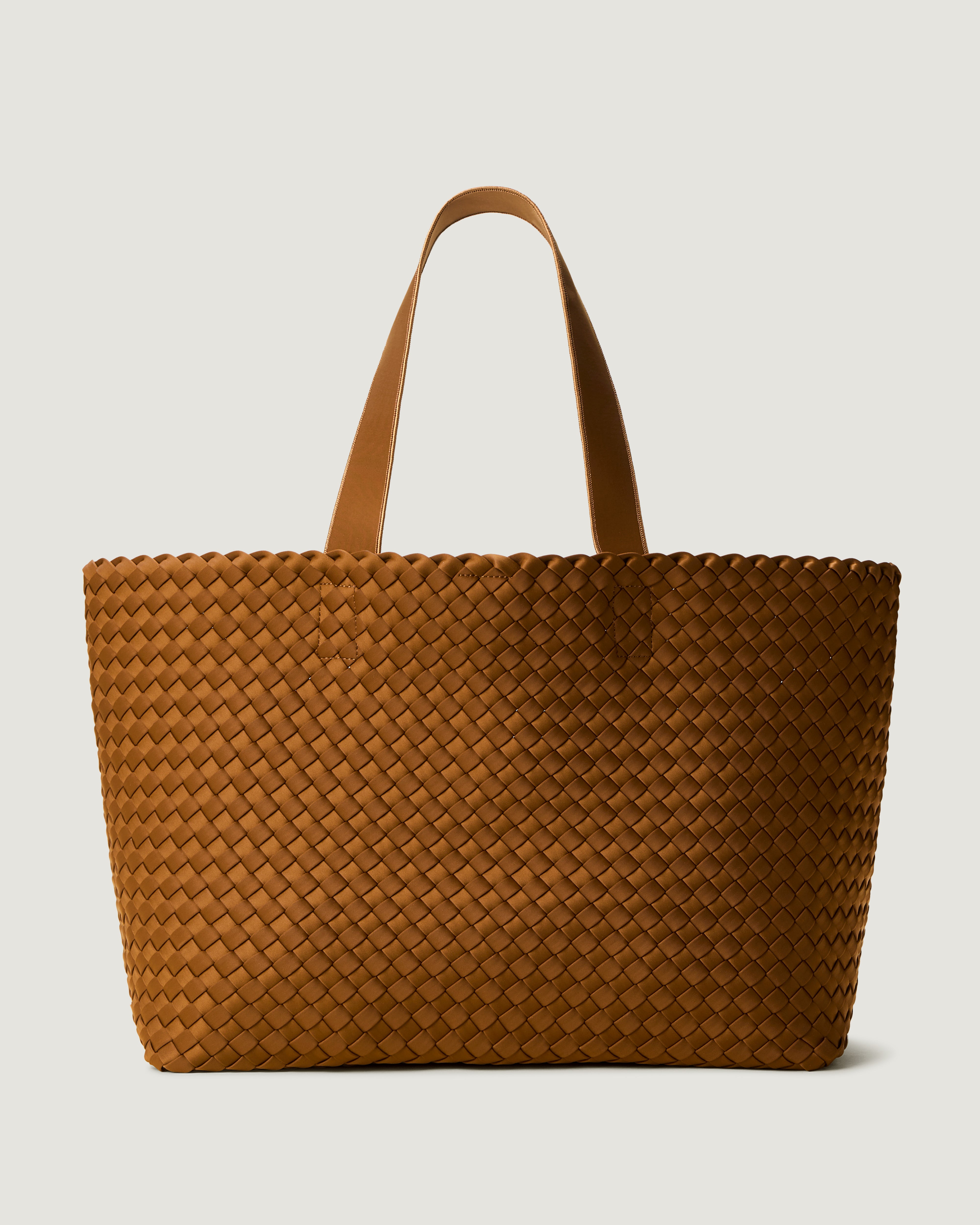 Como Tote in Teak, a saddle brown tone, in handwoven neoprene, featuring an open top with magnetic snap closure, and neoprene shoulder straps.