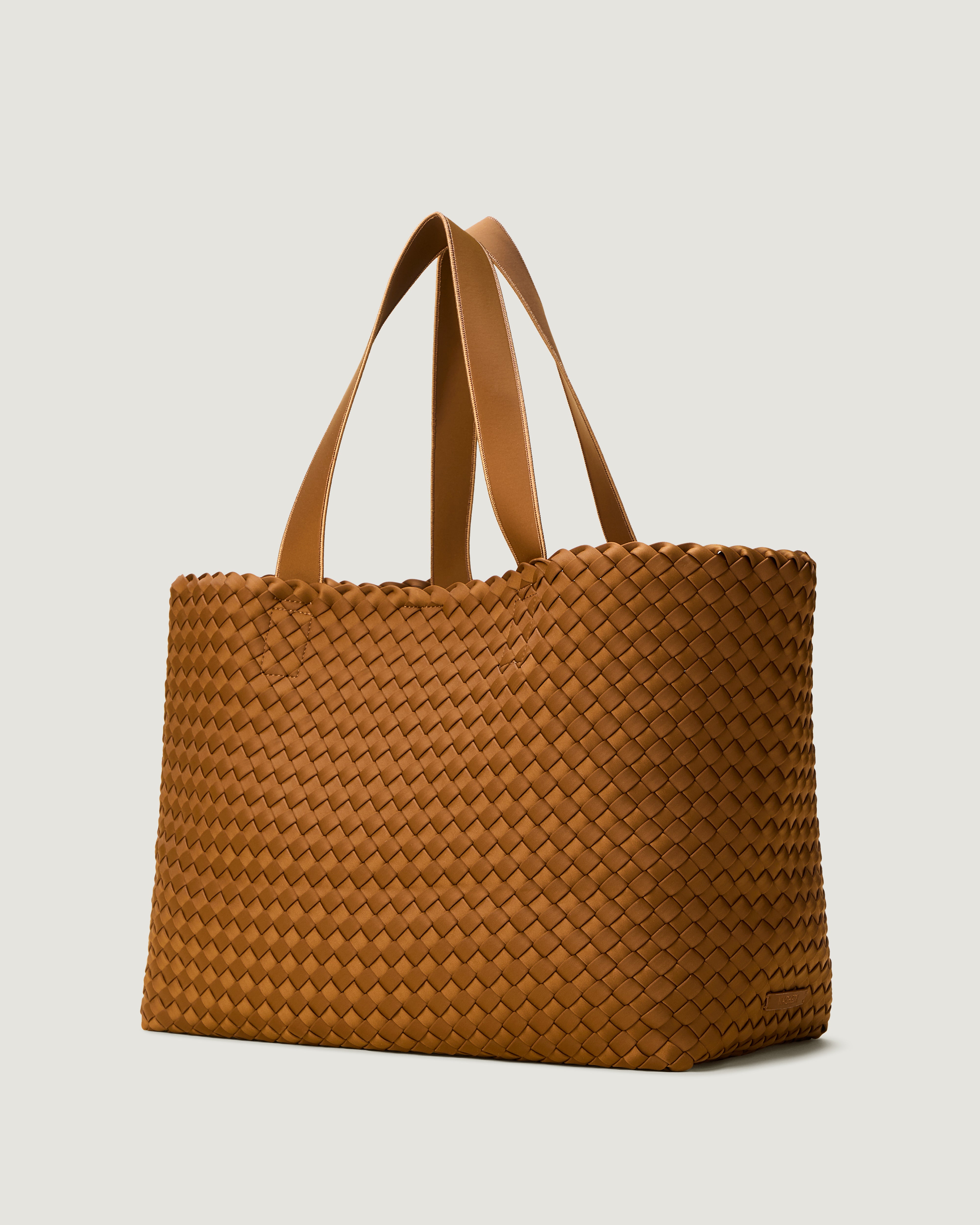 Como Tote in Teak shown from a side angle, highlighting its handwoven neoprene construction and open top with magnetic snap closure.