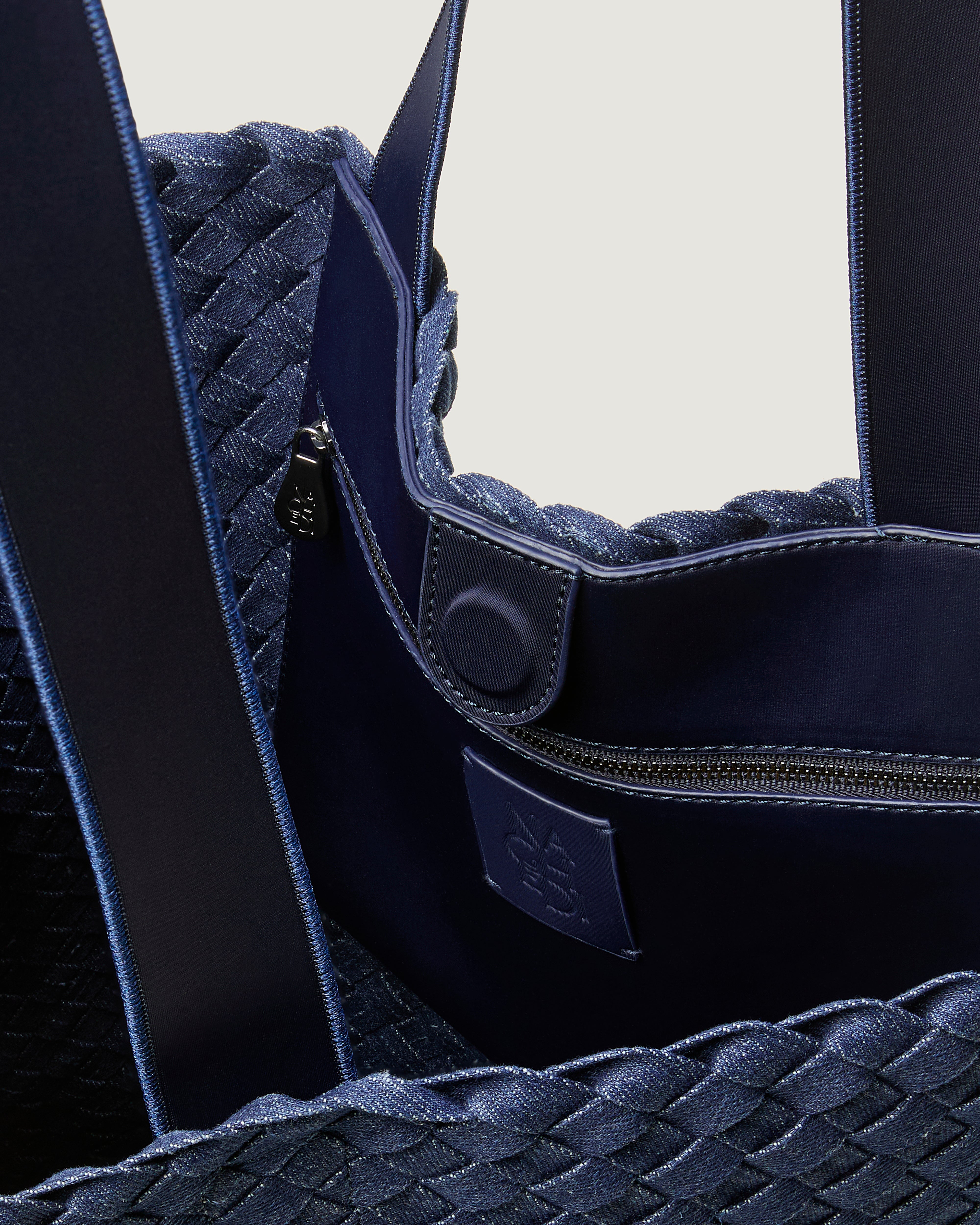 Interior close-up of Como Tote in Denim showing its open top with magnetic snap closure, interior zip pocket, and unlined interior.