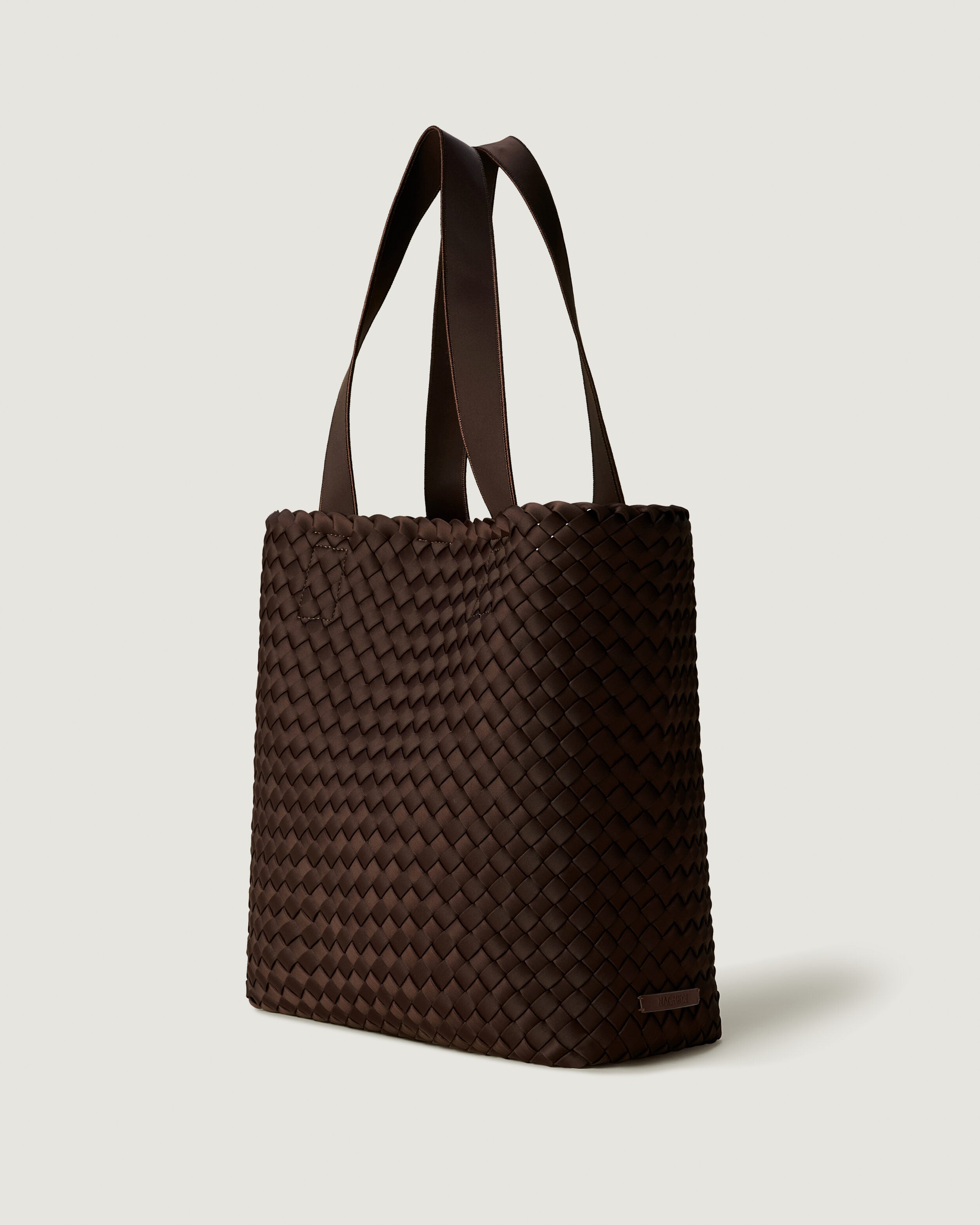 Como Tote in Chocolate shown from a side angle, highlighting its handwoven neoprene construction and open top with magnetic snap closure.