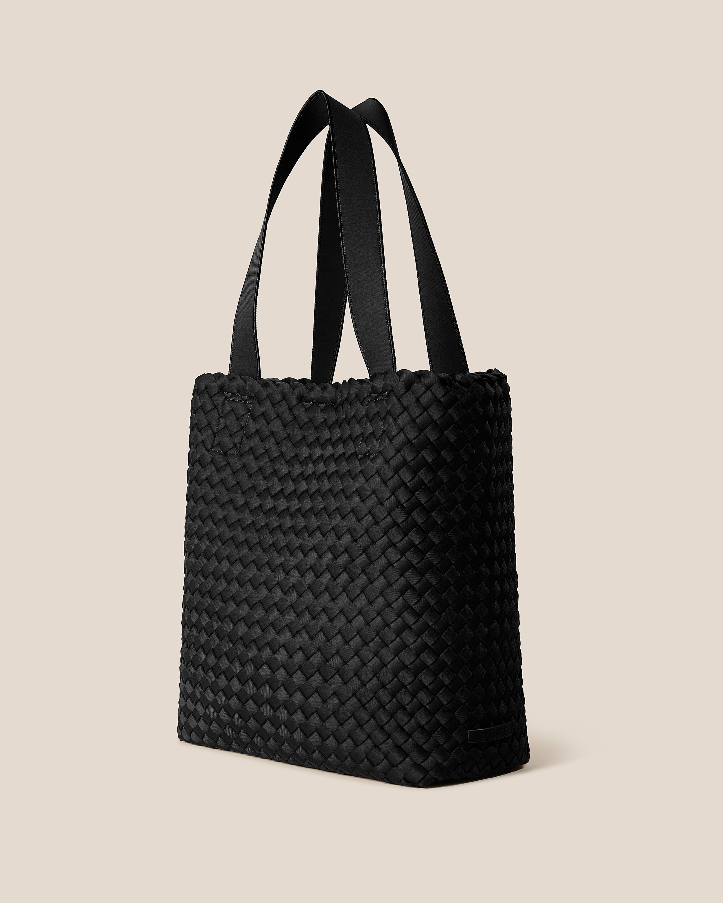 Como Tote in Onyx shown from a side angle, highlighting its handwoven neoprene construction and open top with magnetic snap closure.