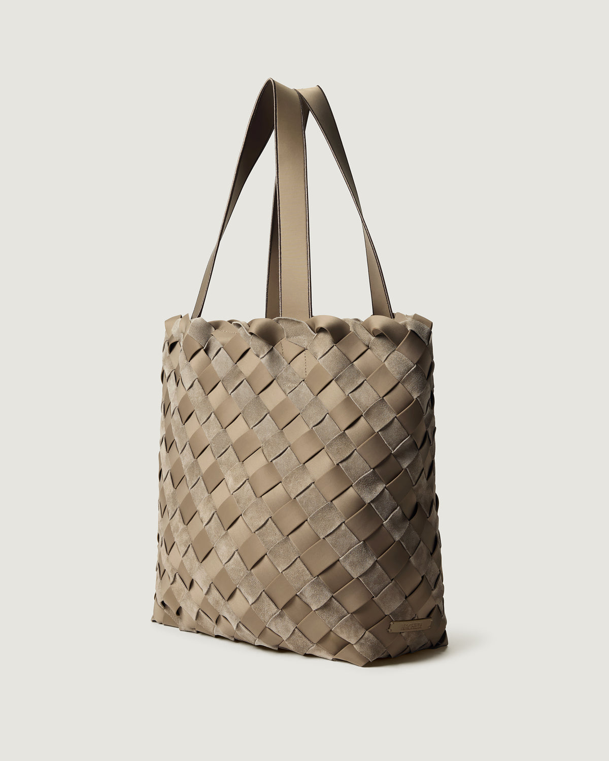 A handwoven suede and neoprene tote bag in a taupe-beige color, featuring a basketweave pattern and two matching shoulder straps.