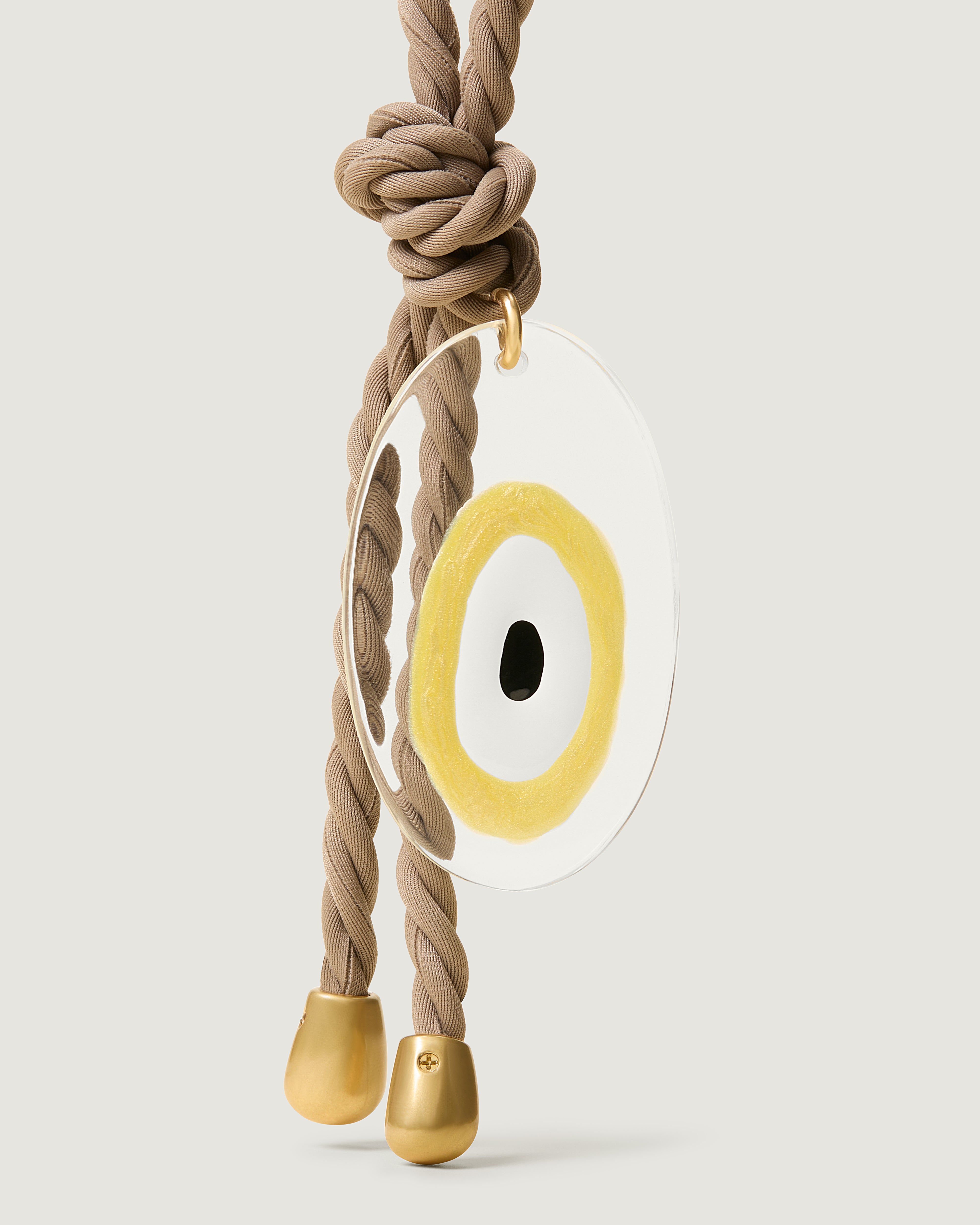 Close up of the Evil Eye Bag Charm in Cashmere. Highlighting the Evil Eye pendant and brushed gold hardware tips.