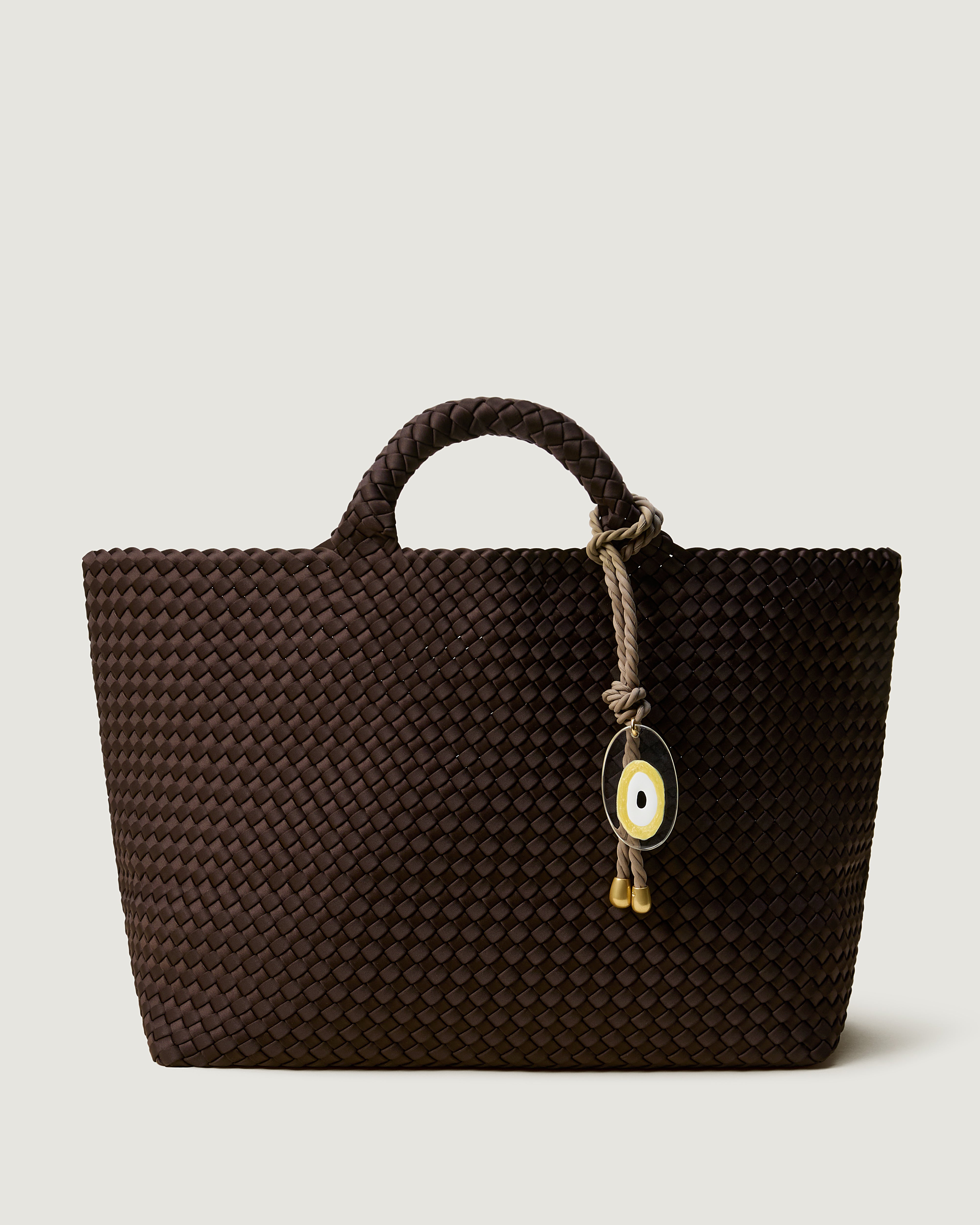 St. Barths Tote in Chocolate, a rich brown tone, in handwoven neoprene, featuring an open top, and woven top handles with Cashmere Evil Eye rope bag charm.
