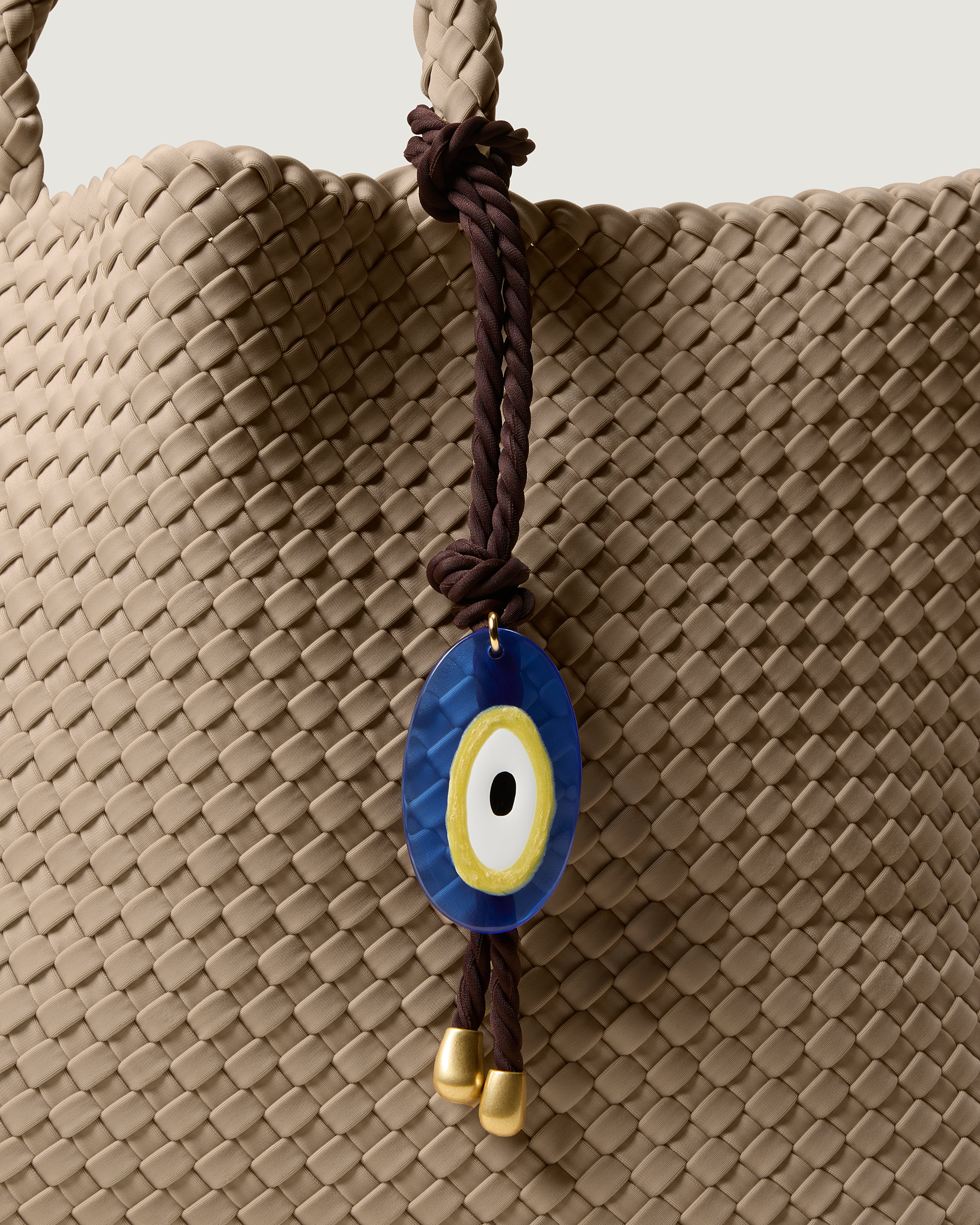 Close up of Evil Eye Charm in Chocolate hanging from St. Barths Large Tote in Cashmere.