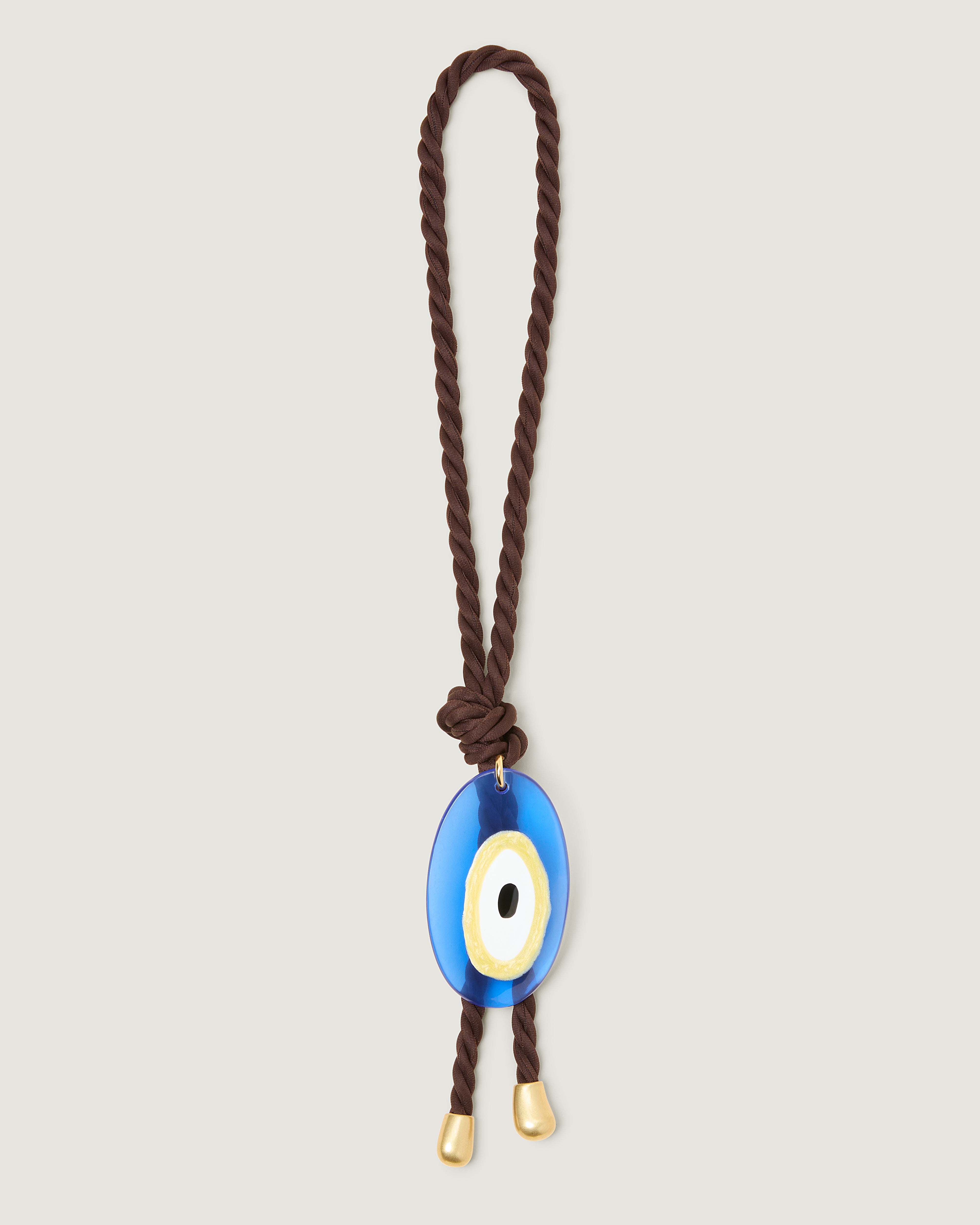 Chocolate brown neoprene rope bag charm featuring a blue evil eye pendant, finished with gold tips and knotted detail.
