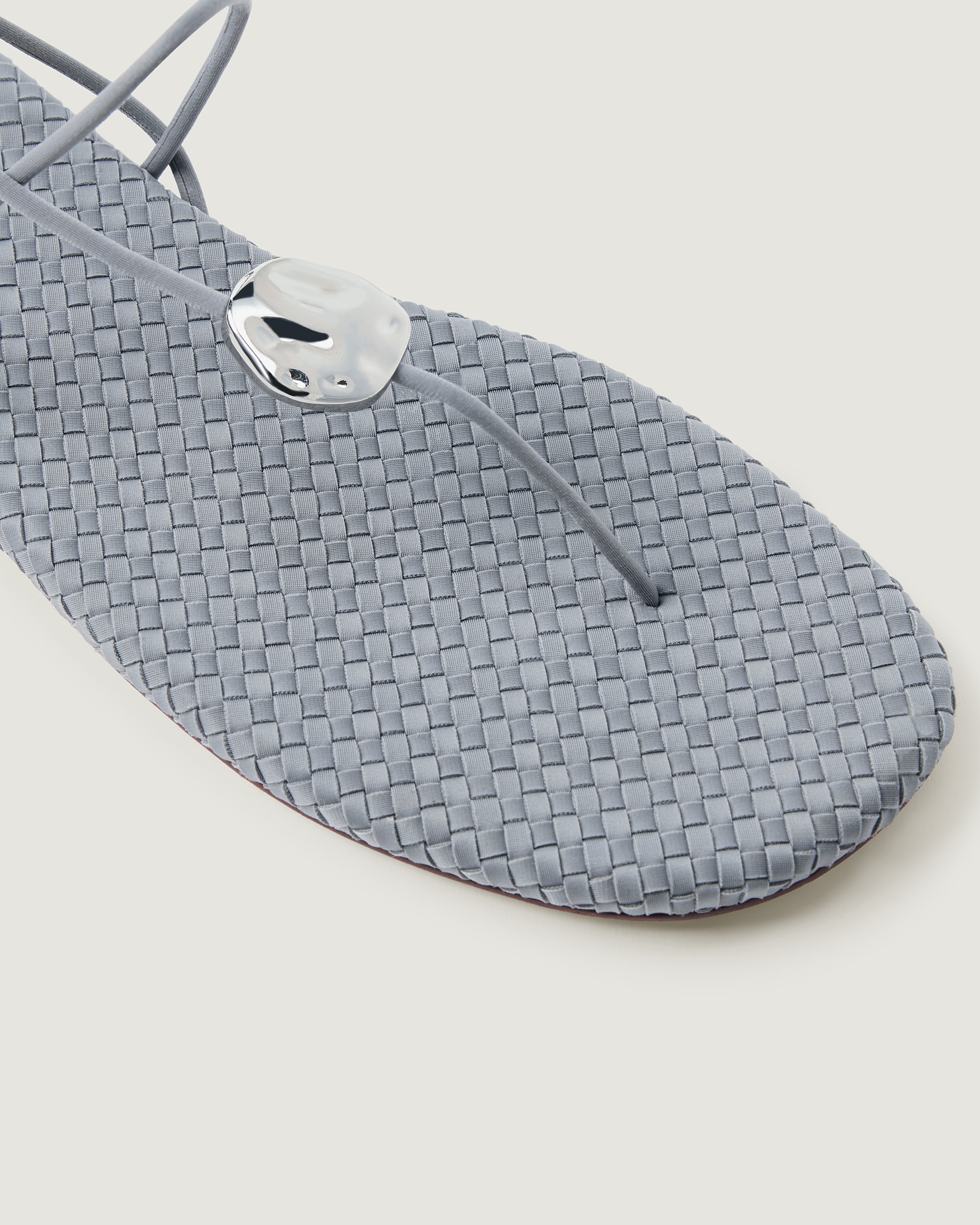 Close-up of The Gaia Sandal in Marina showing its hammered metallic disc detail.