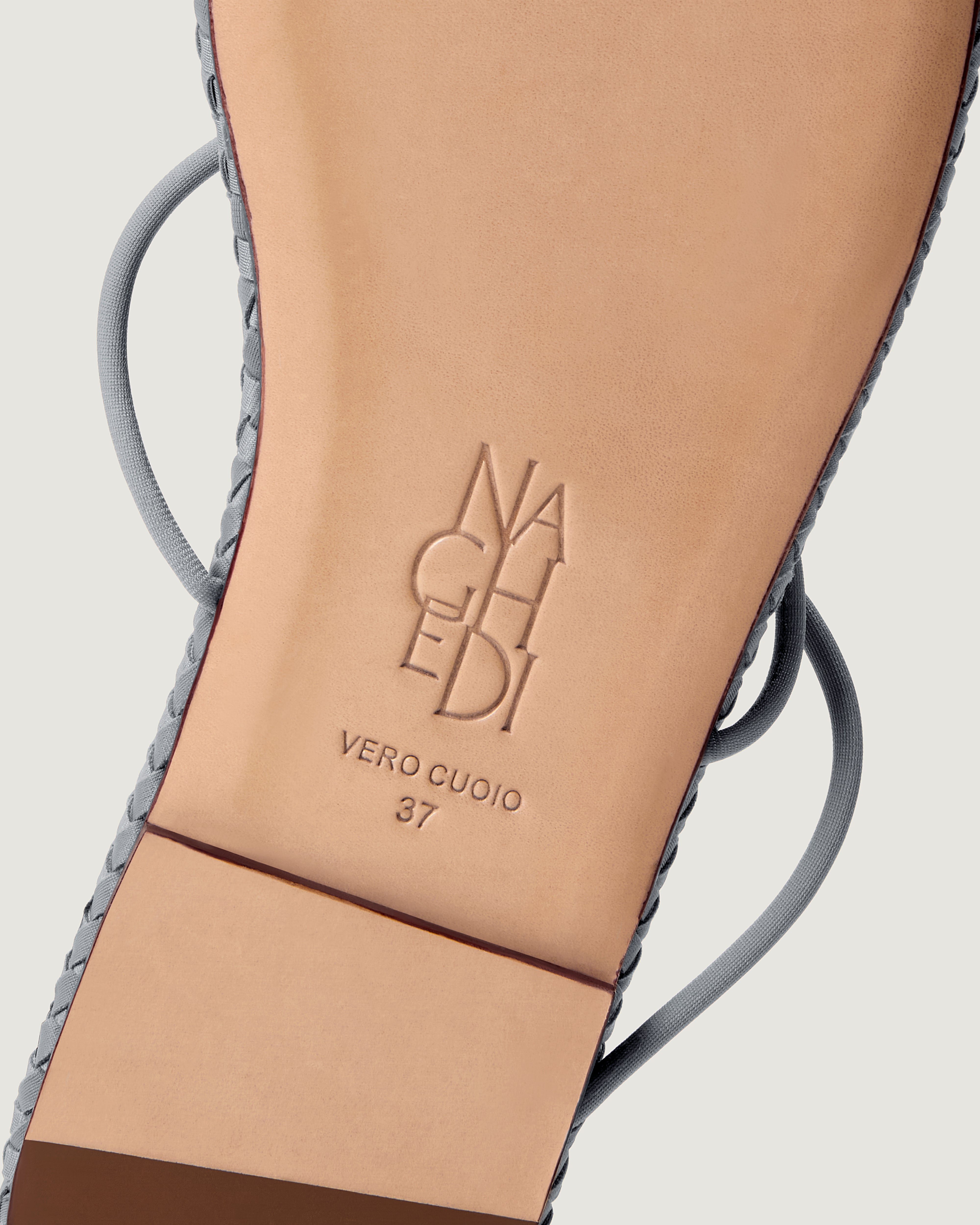 Shoe sole showing natural buffed leather sole, stamped NAGHEDI logo and size detail for Gaia Sandal in Marina.