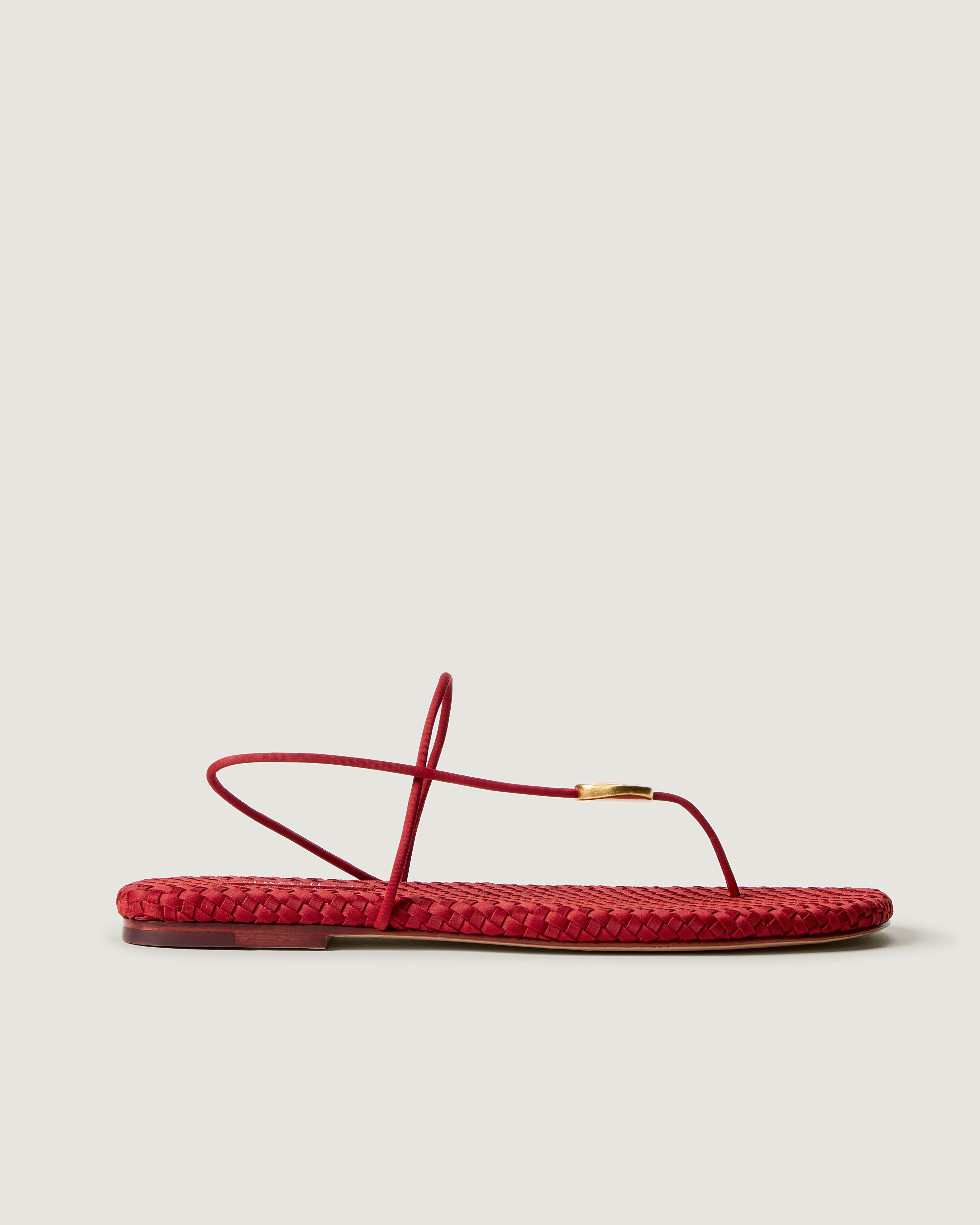 Side view of Gaia Sandal in Rosso, a rich red tone, featuring 2 thin straps and hammered metallic disc detail.