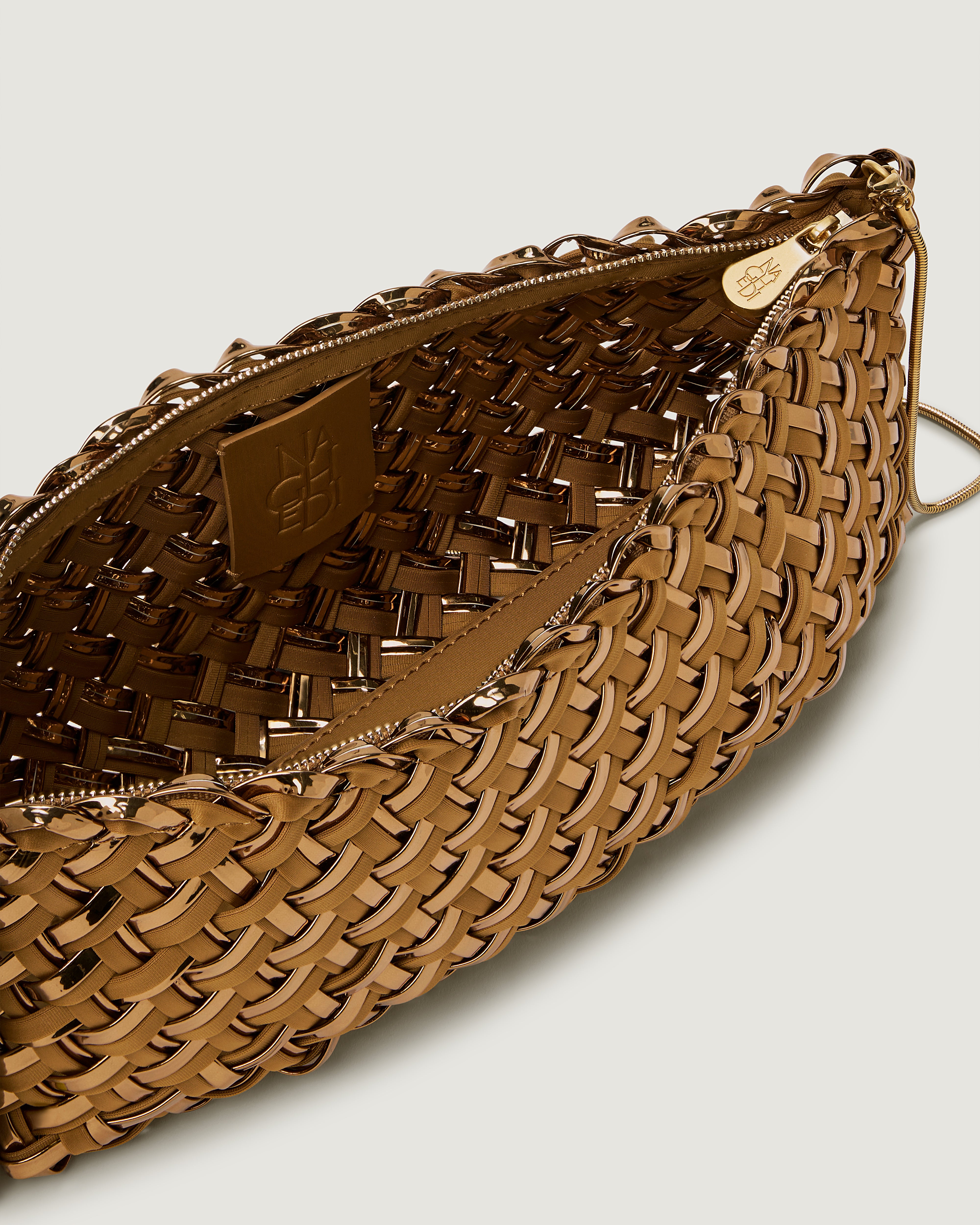 Closeup photo of the interior of a handwoven neoprene and satin shoulder bag in gold.