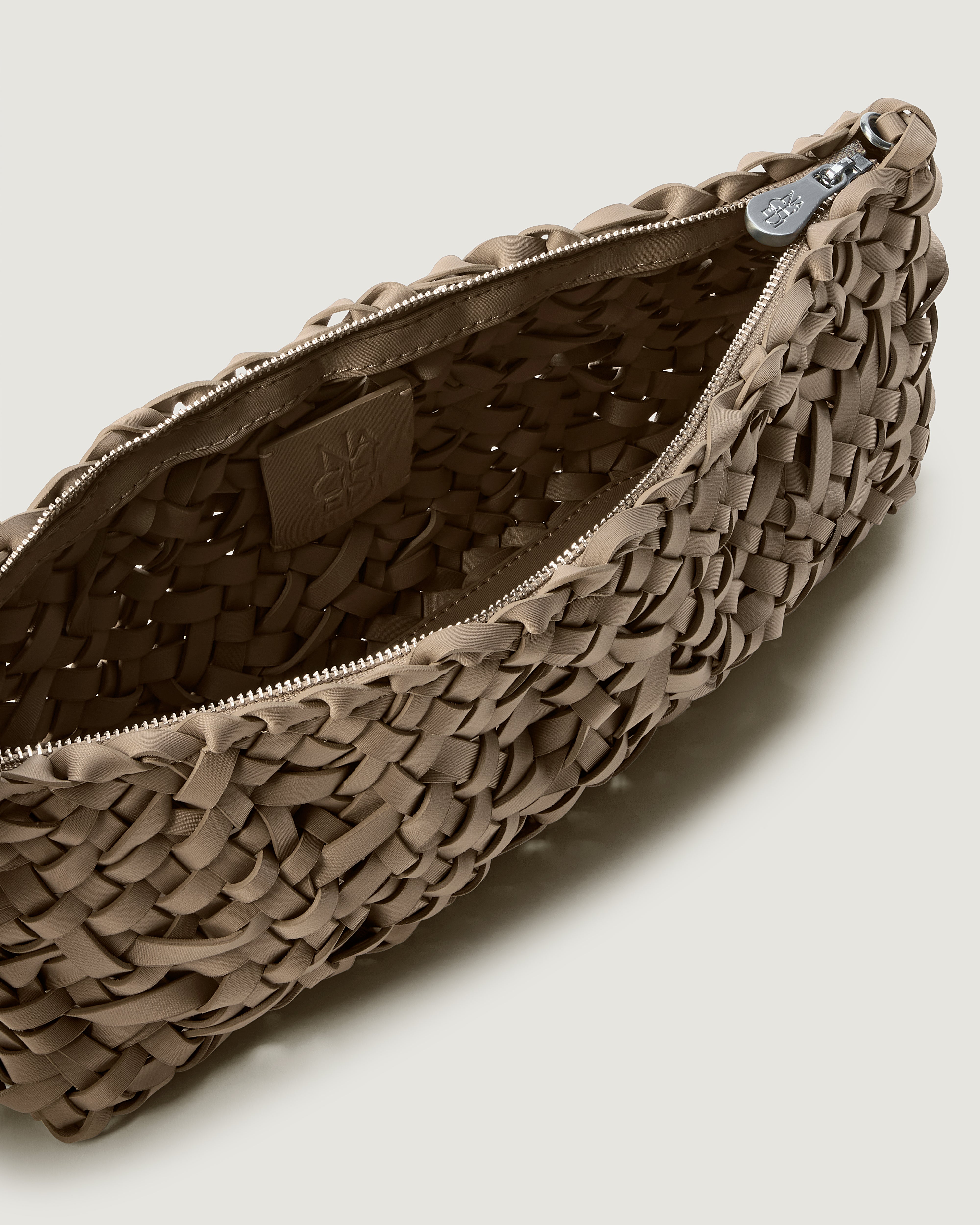 Close up of interior of handwoven neoprene shoulder bag in cool taupe color with a crosshatch nest weave pattern and silver hardware