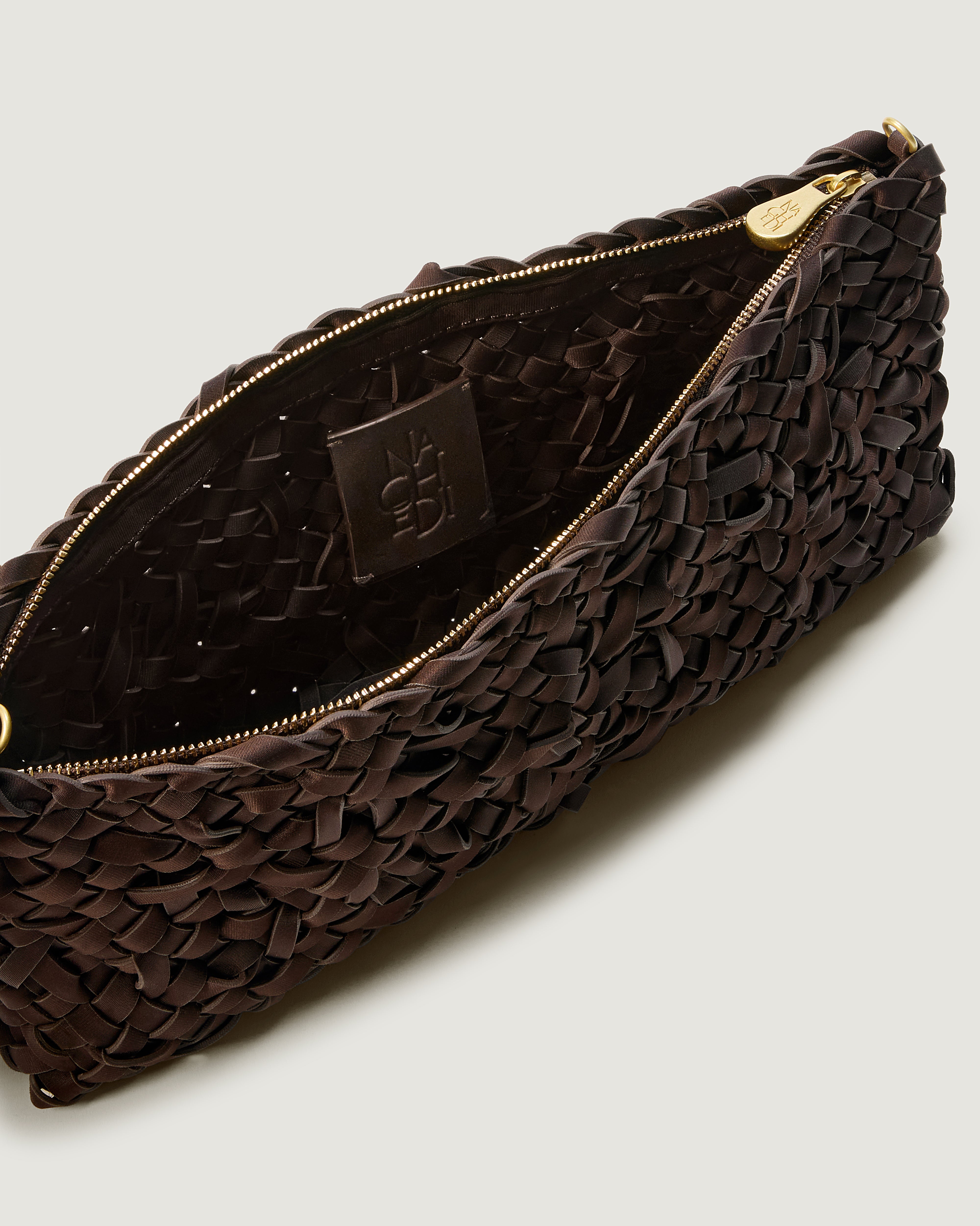 Close up of interior of handwoven neoprene shoulder bag in chocolate brown color with a crosshatch nest weave pattern and gold hardware