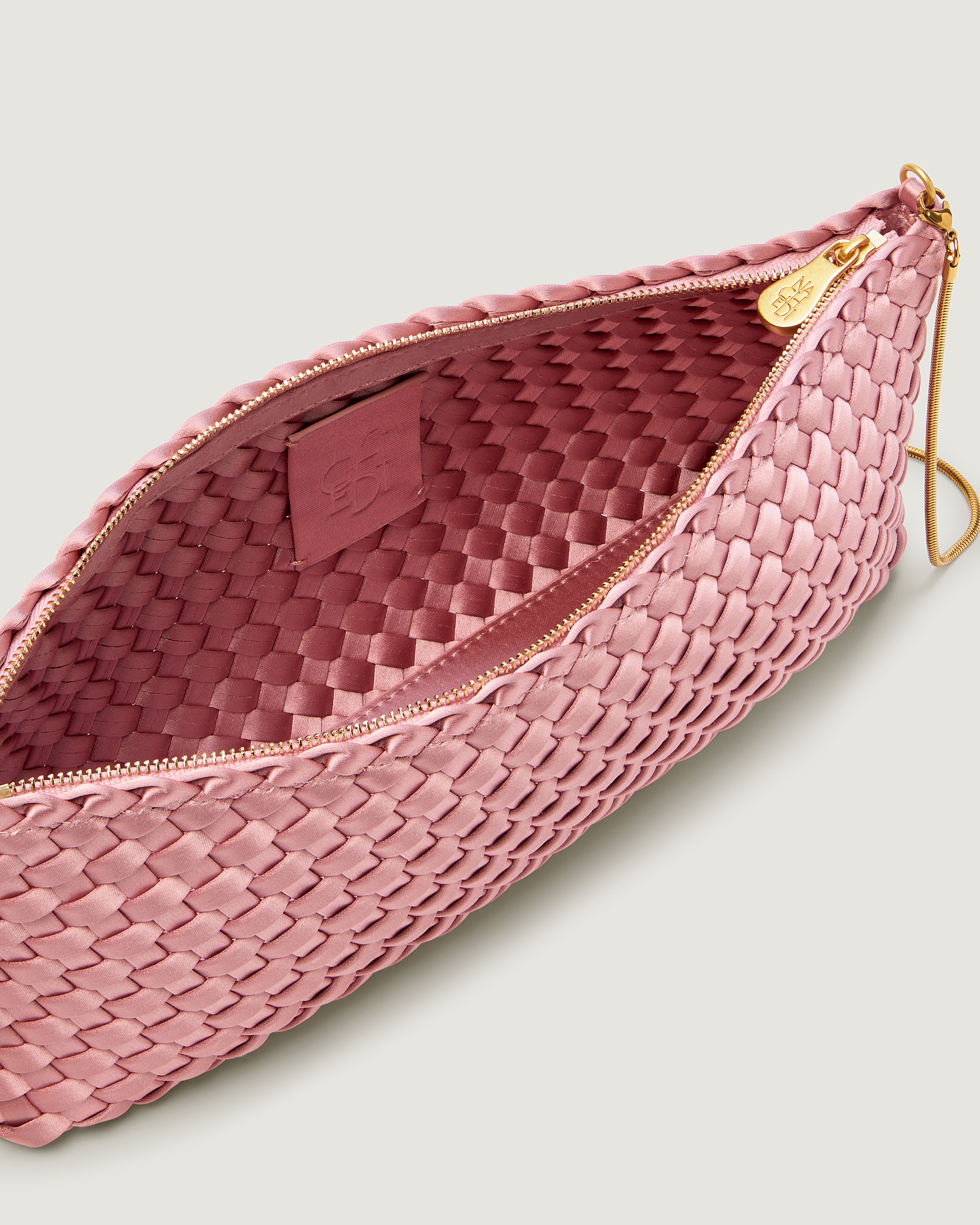 An interior shot of a handwoven satin neoprene shoulder bag in pink with a thin gold metal chain strap.