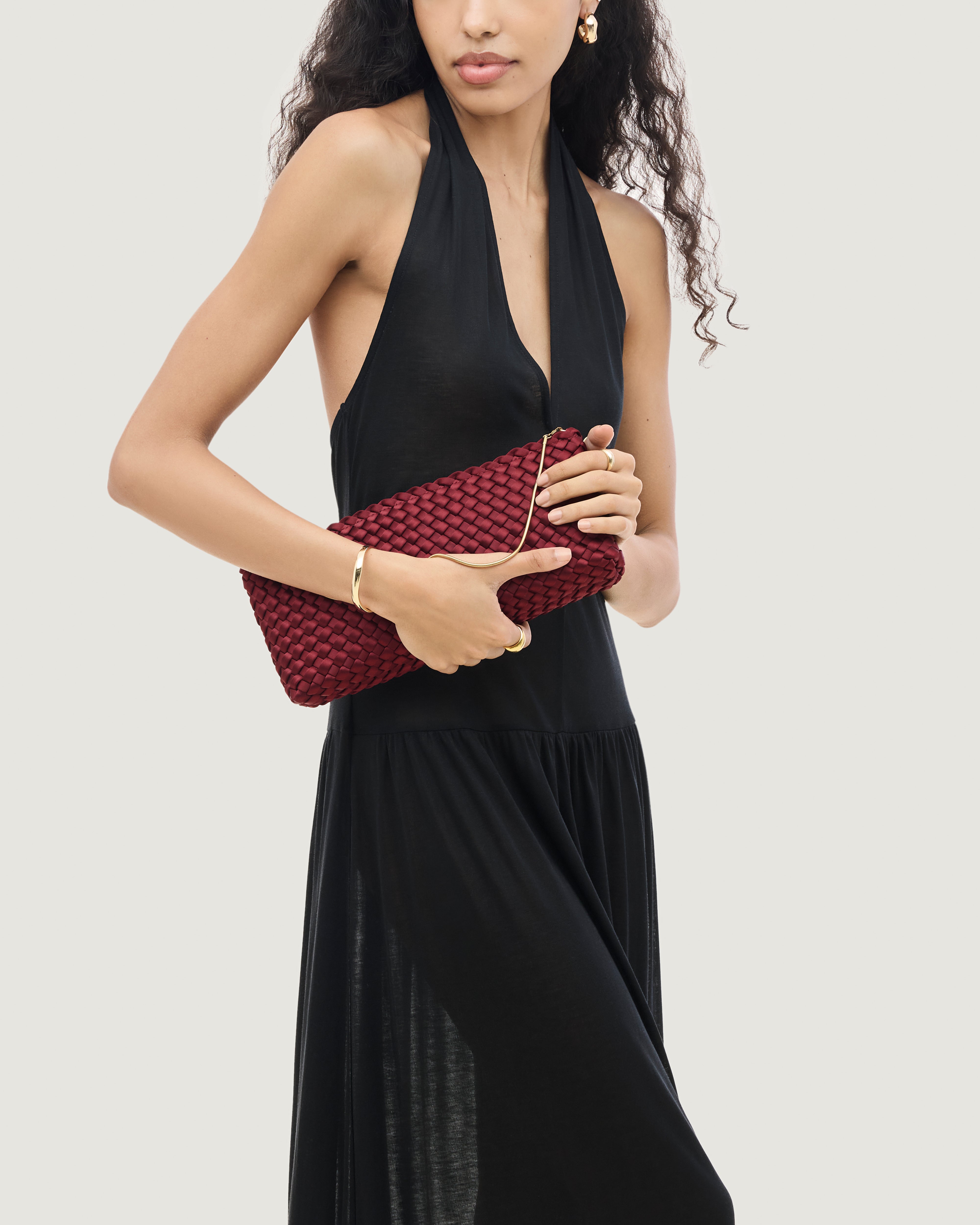 On model close up of the Gala Clutch in Garnet. Highlighting the handwoven satin and the removable gold chain.