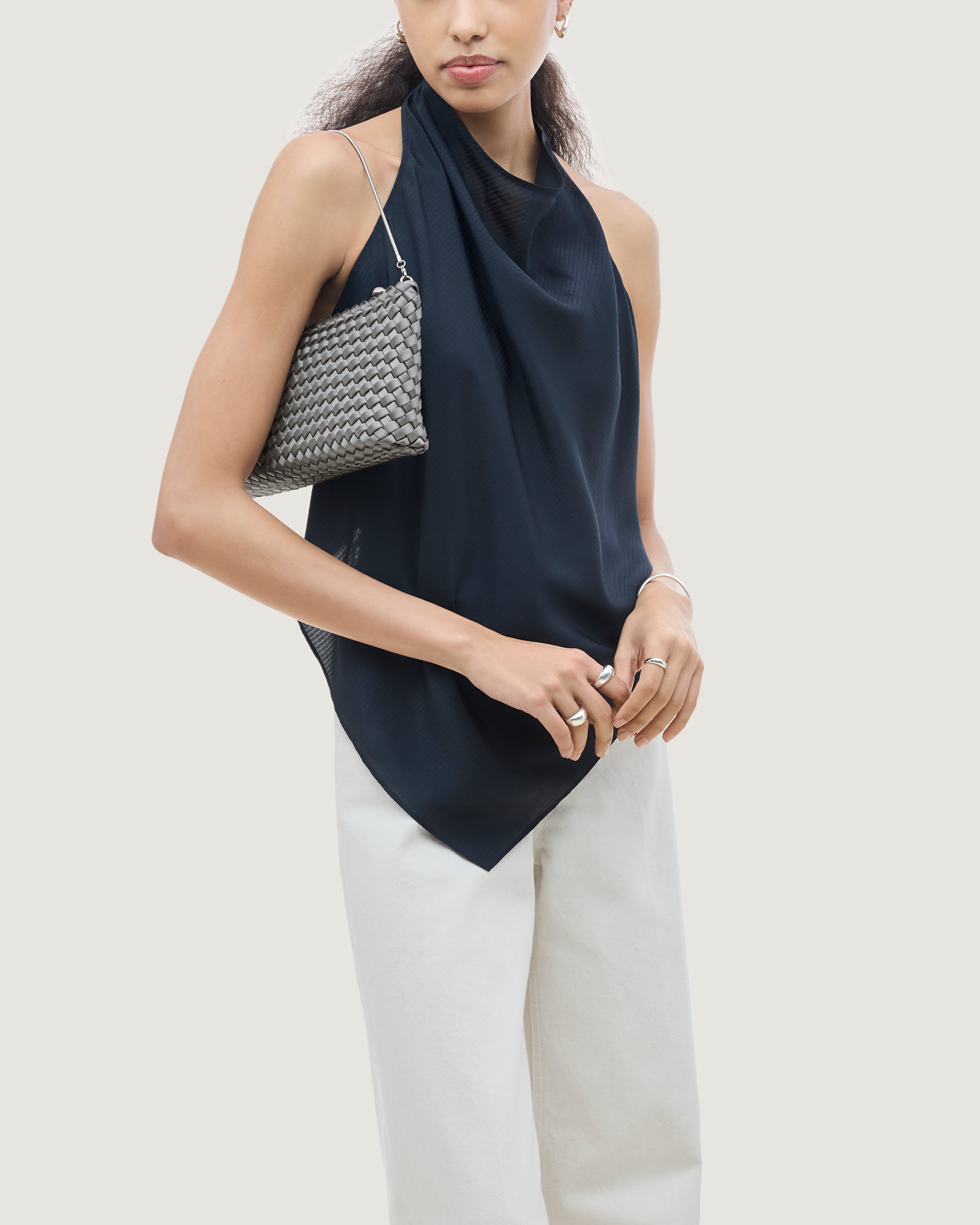 On model close up of the Gala Clutch in Graphite. Highlighting the handwoven satin and the removable silver chain.