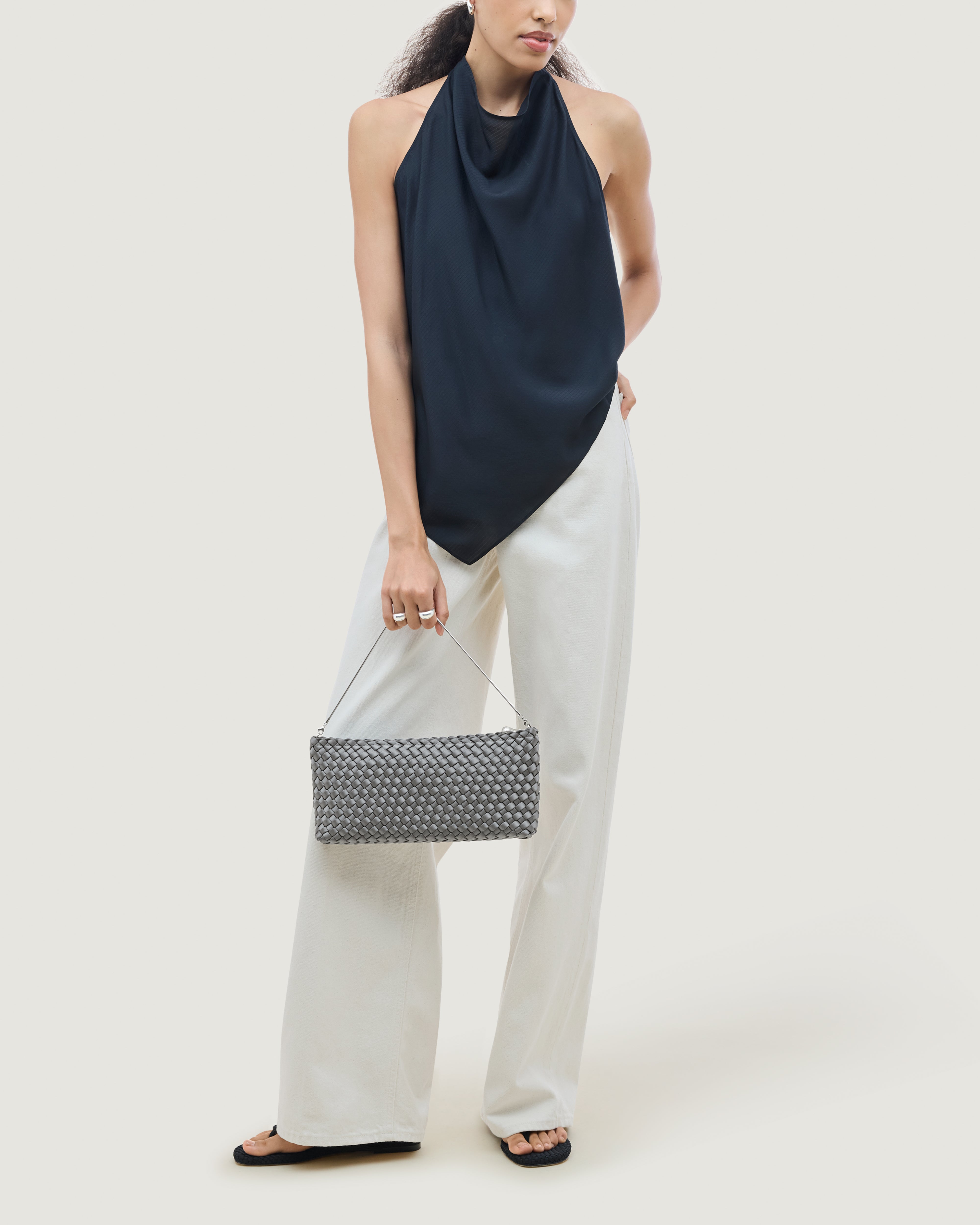 On model close up of the Gala Clutch in Graphite. Highlighting the handwoven satin and the removable silver chain.
