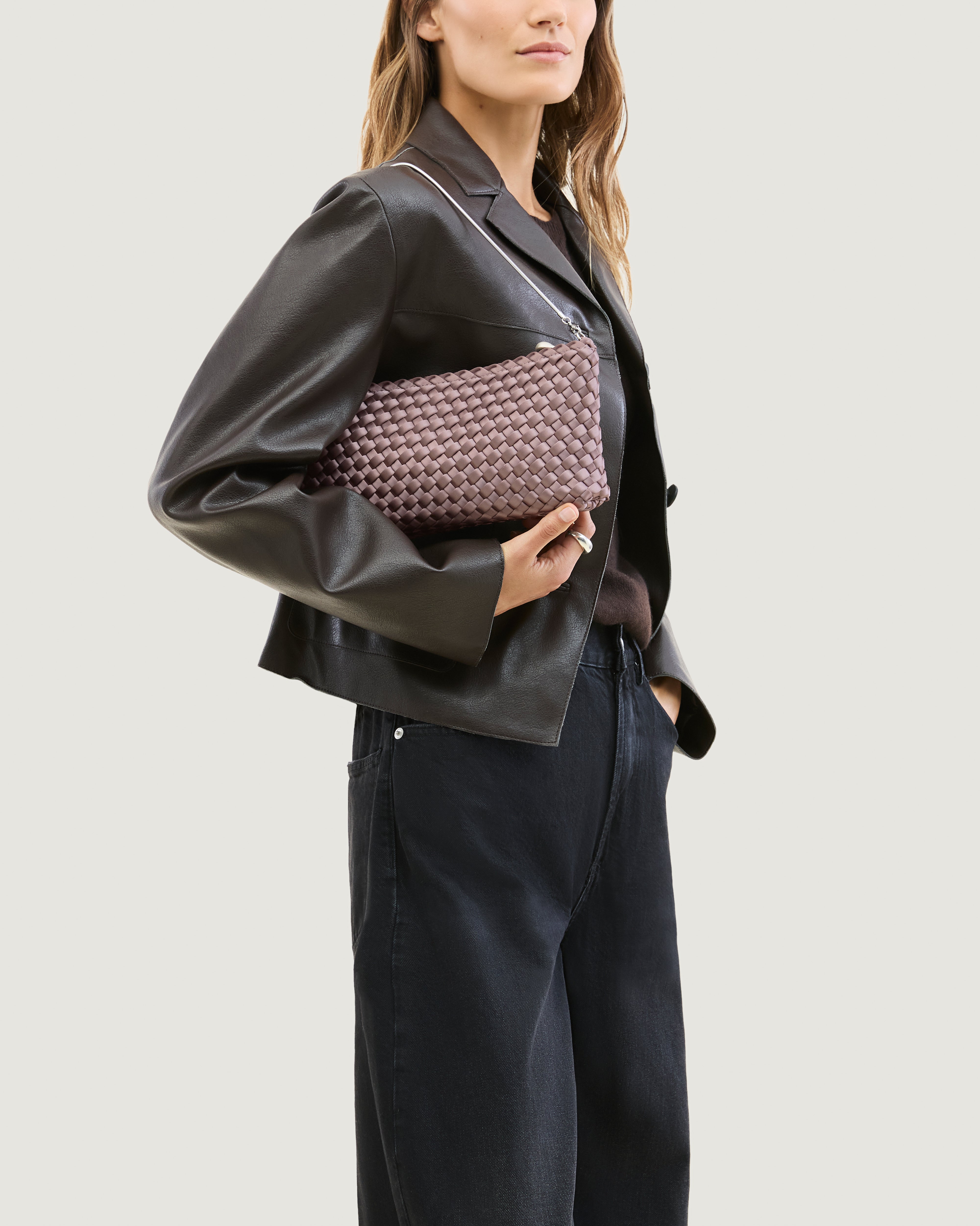 Model holding a handwoven satin neoprene shoulder bag in lavender with a thin silver metal chain strap.