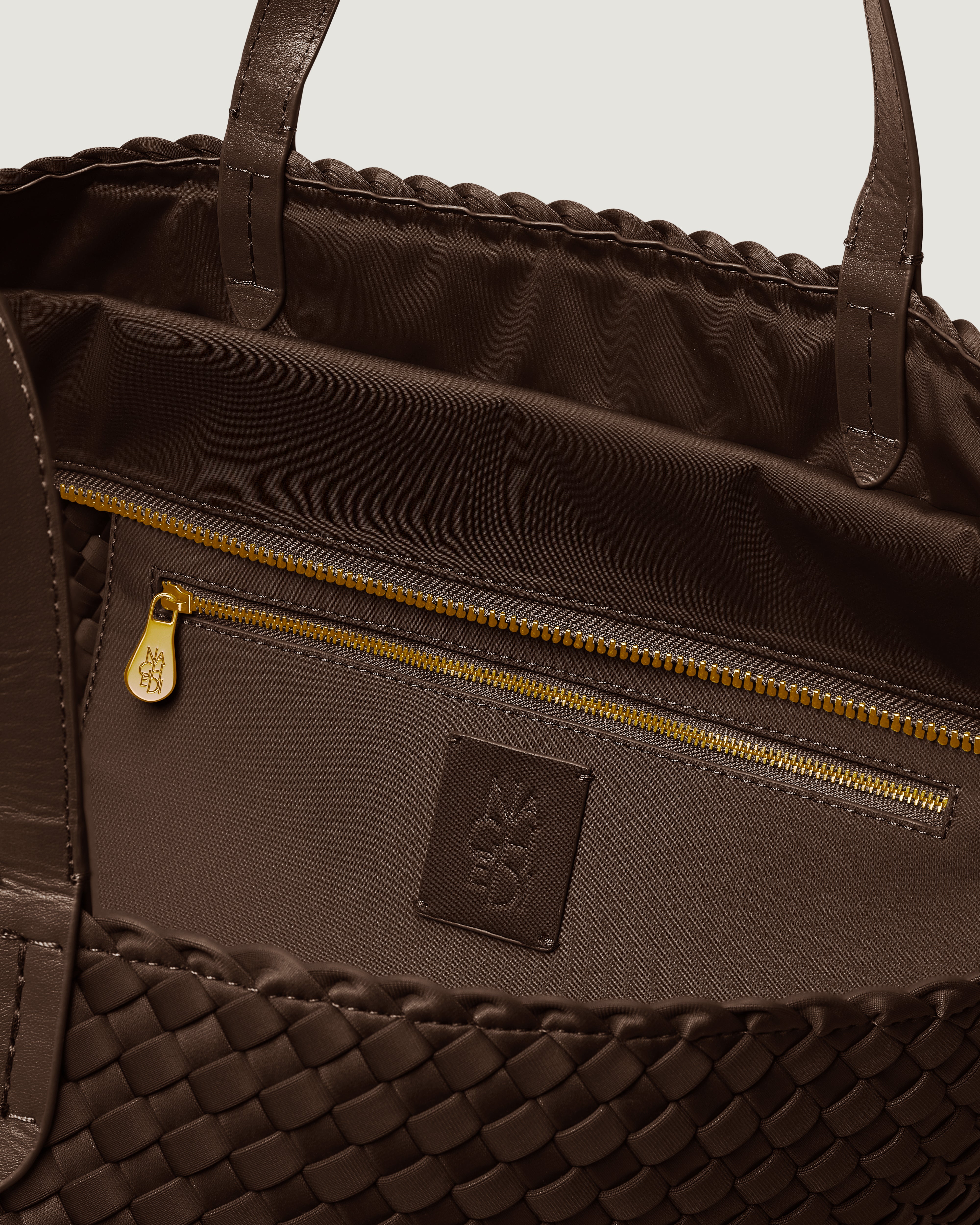 Interior close-up of Geneva Weekender in Chocolate showing its top zip closure, interior pocket, and unlined interior.