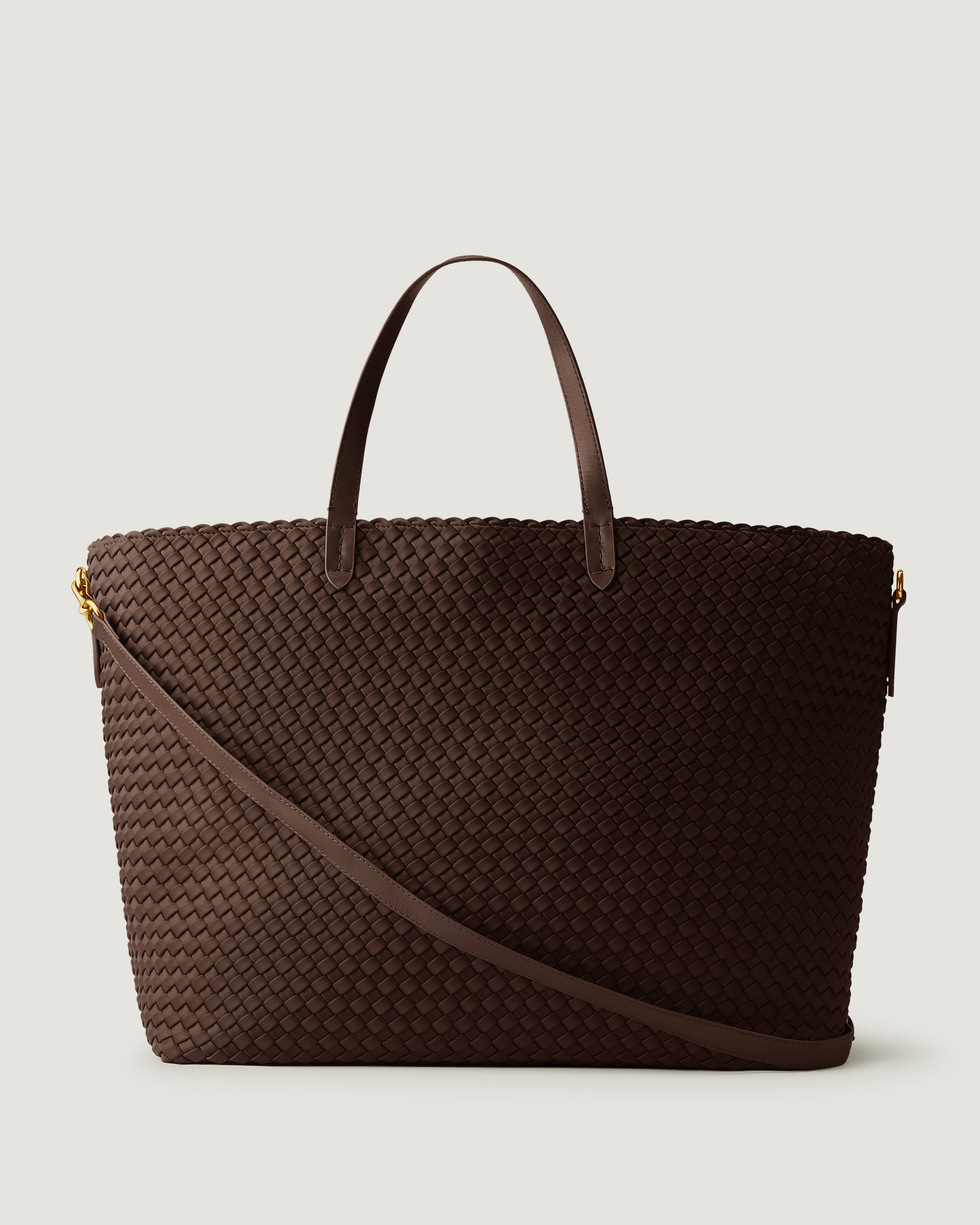 Geneva Weekender in Chocolate, a dark brown tone, in handwoven neoprene, featuring a top zip closure, leather handles, and detachable, adjustable leather strap.