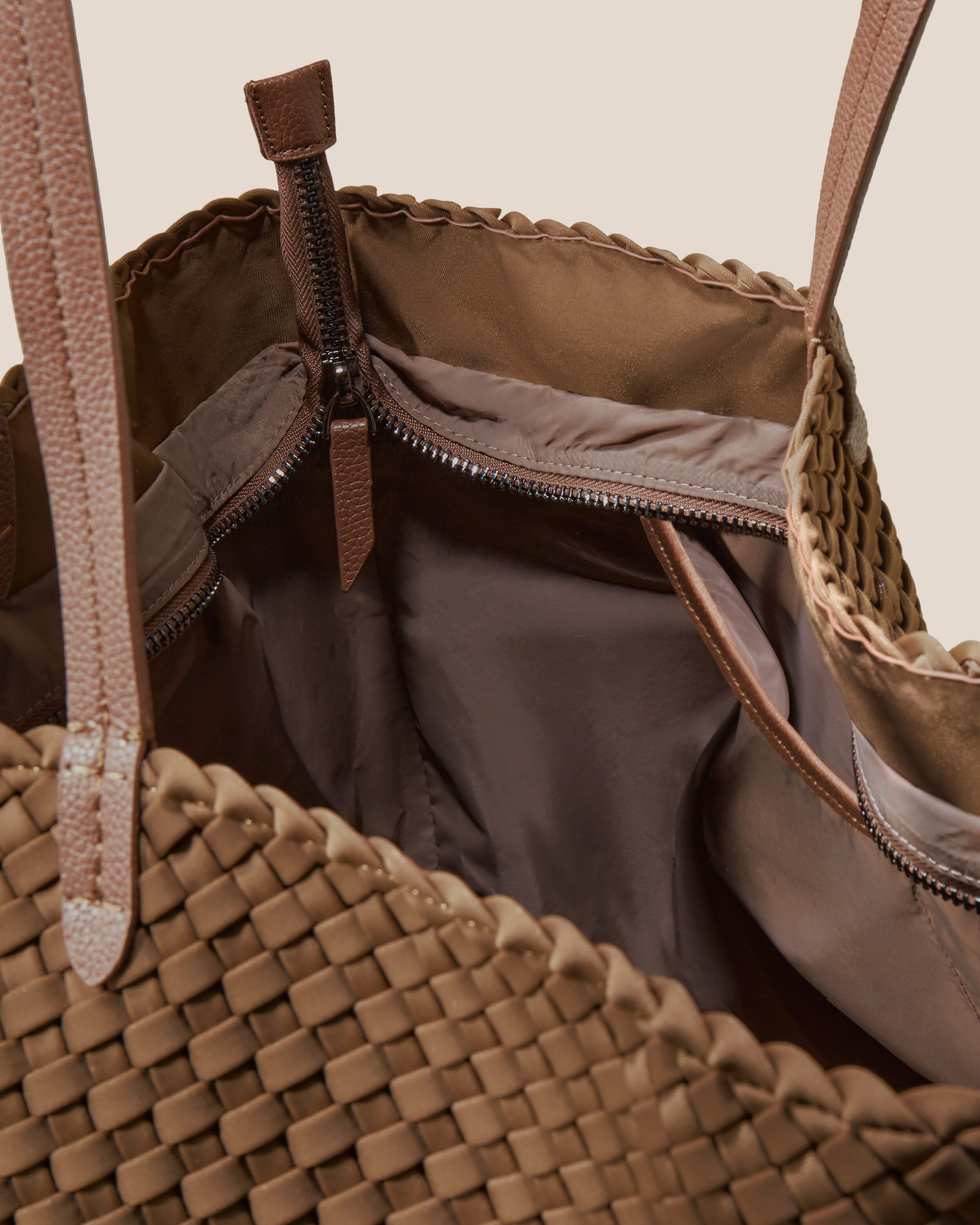 Interior close-up of Geneva Weekender in Mink showing its top zip closure, interior pockets, and wipe-clean nylon interior.