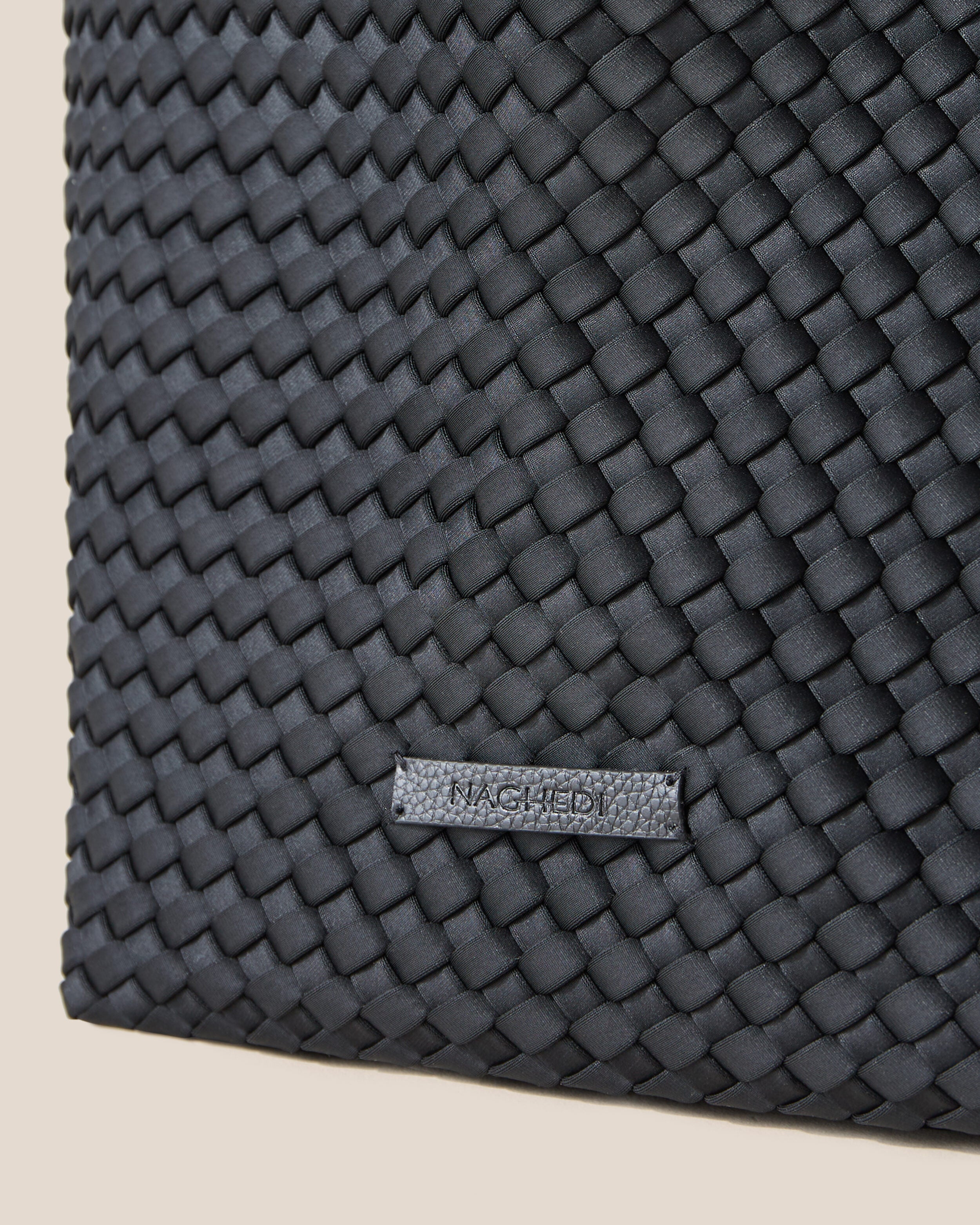 Close-up of stamped NAGHEDI logo on Geneva Weekender in Onyx.