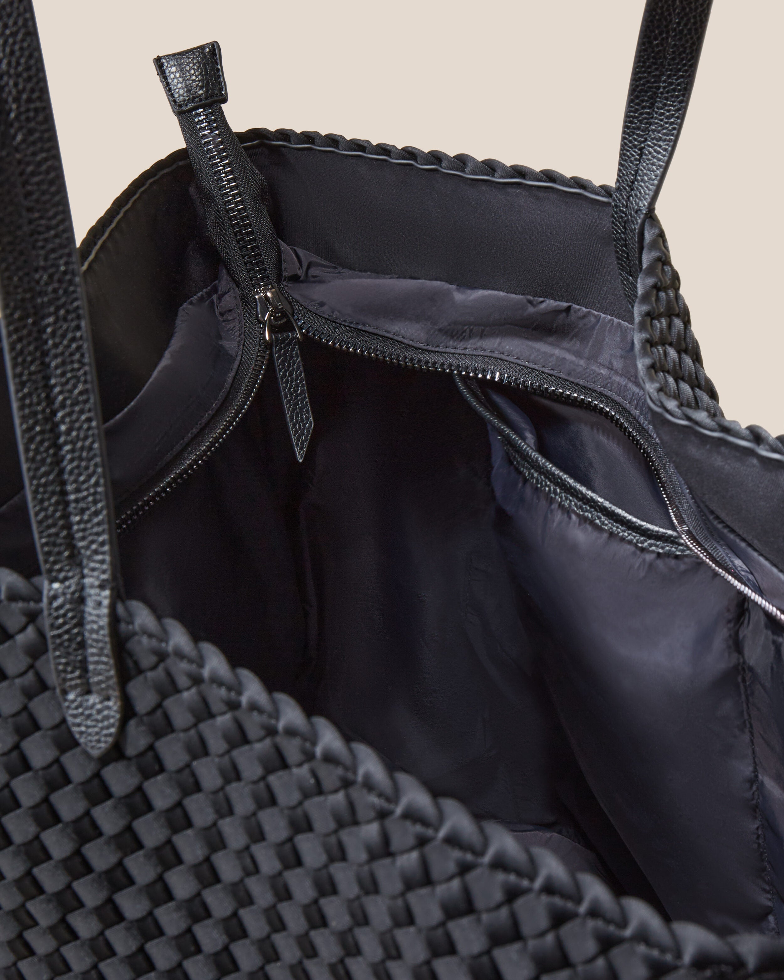 Interior close-up of Geneva Weekender in Onyx showing its top zip closure, interior pockets, and wipe-clean nylon interior.