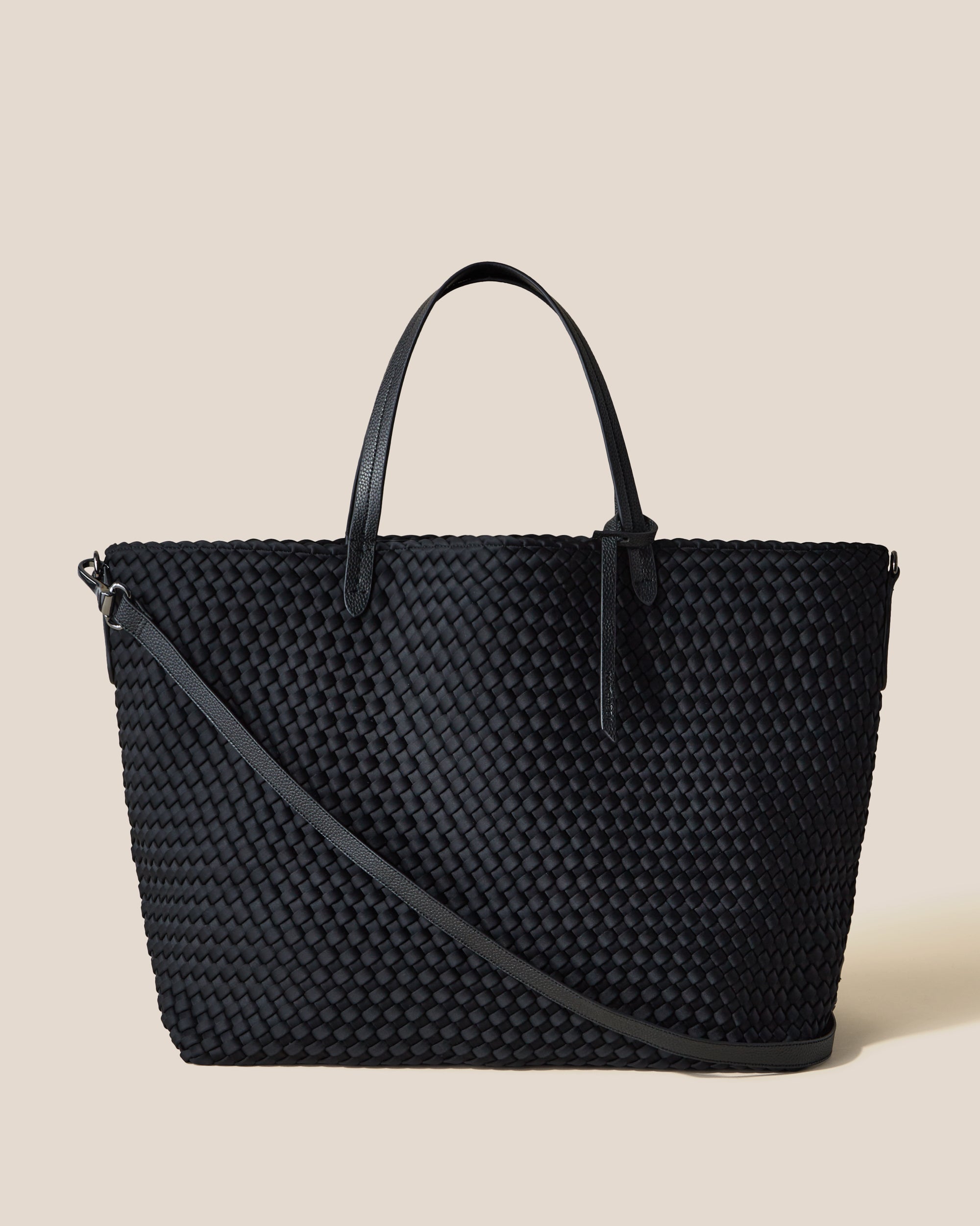 Geneva Weekender Bag in Onyx, a true black tone, in handwoven neoprene featuring a top zip closure, vegan leather handles, and detachable, adjustable vegan leather strap.