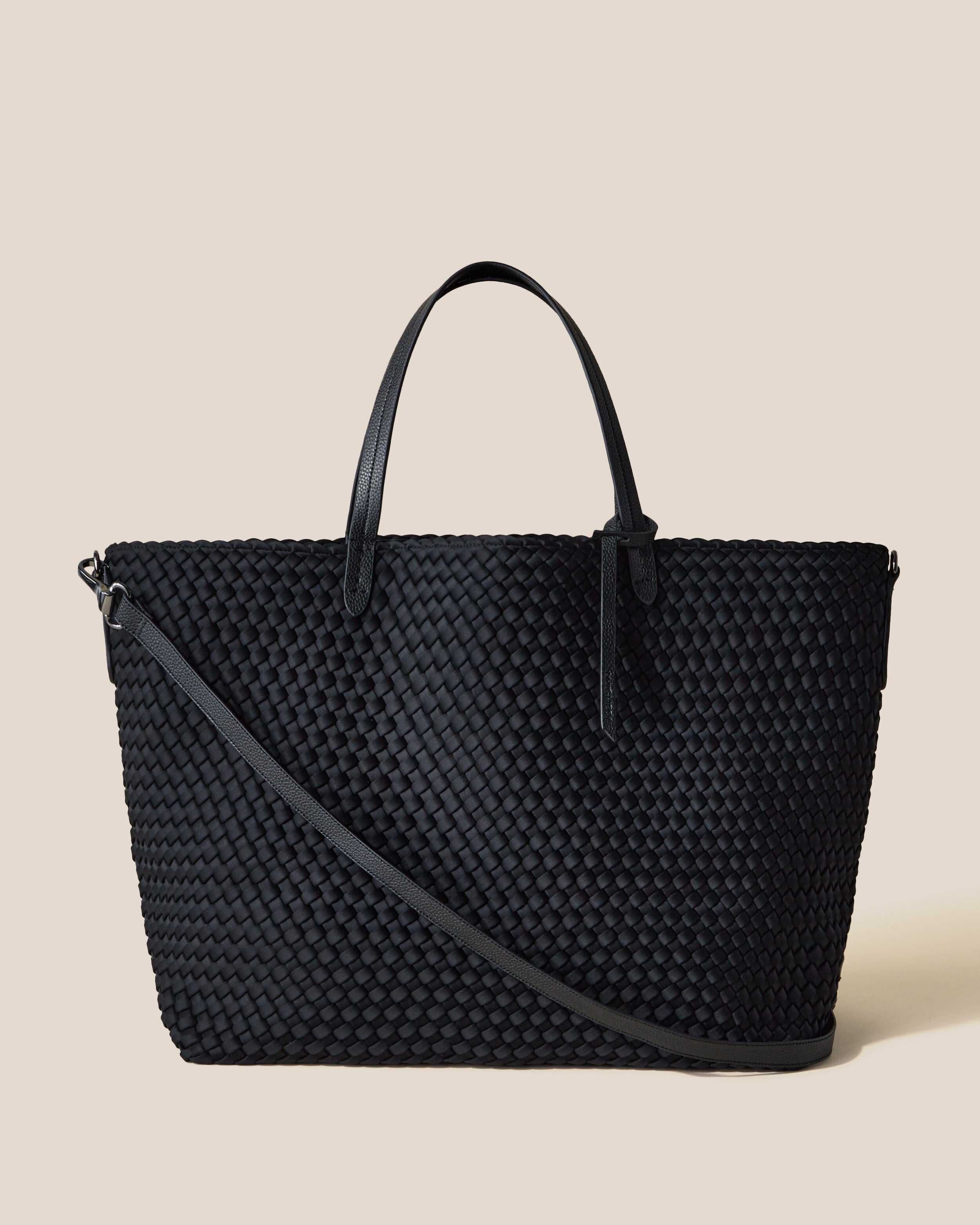 Geneva Weekender in Onyx, a true black tone, in handwoven neoprene, featuring a top zip closure, vegan leather handles, and detachable, adjustable vegan leather strap.
