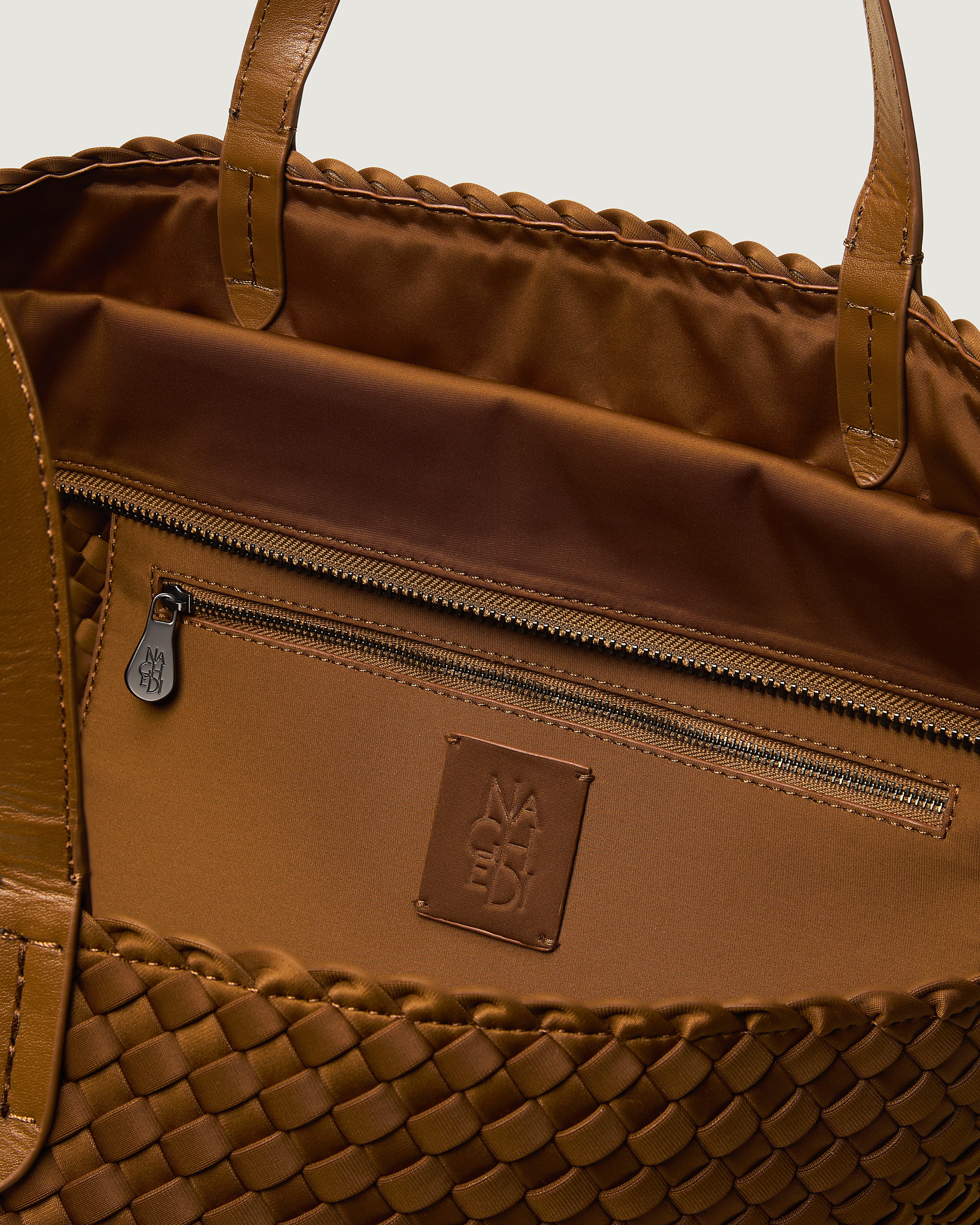 Interior close-up of Geneva Weekender in Teak showing its top zip closure, interior pocket, and unlined interior.