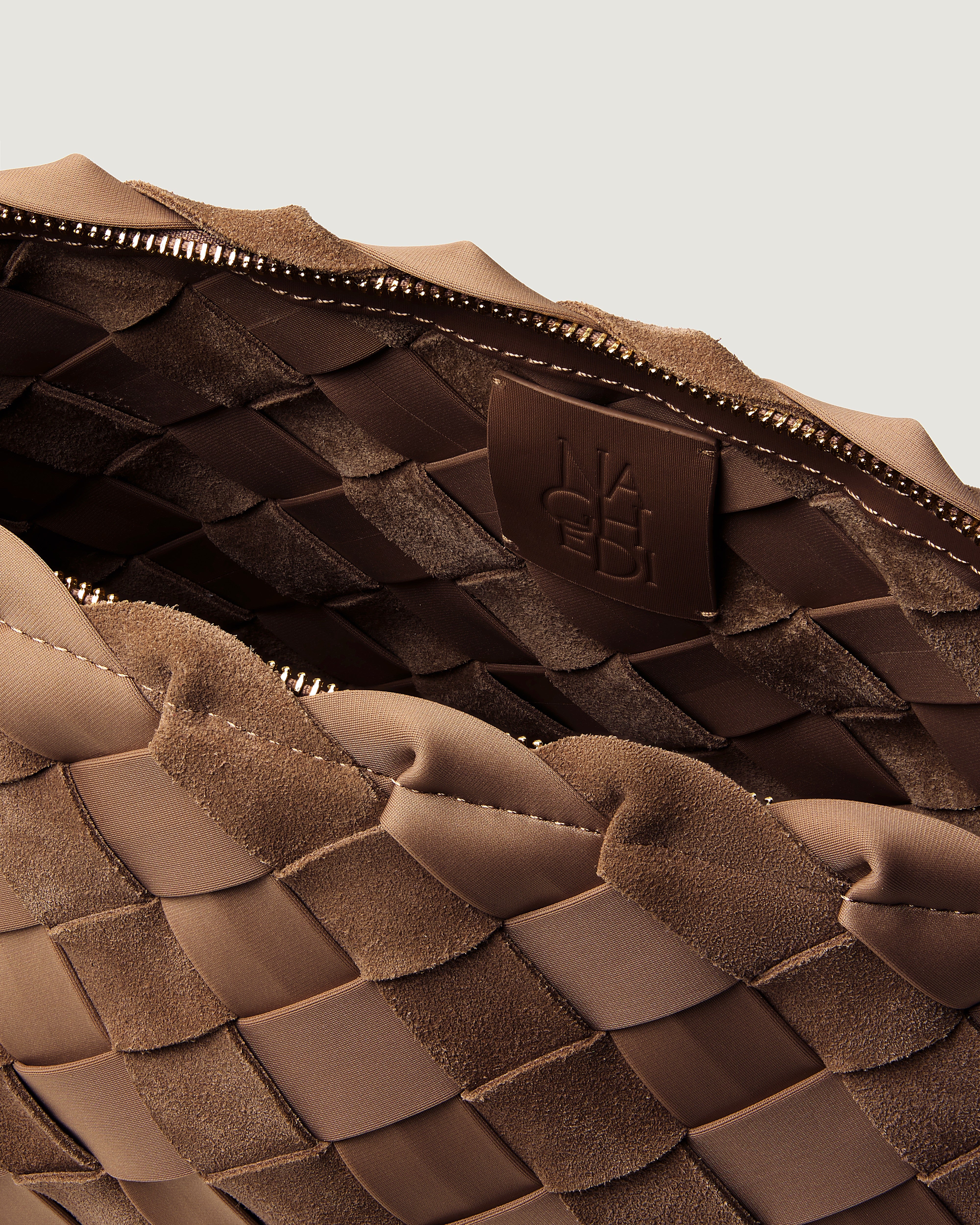 Close-up of a large handwoven suede and neoprene pouch in a medium brown shade, featuring a top zipper closure.